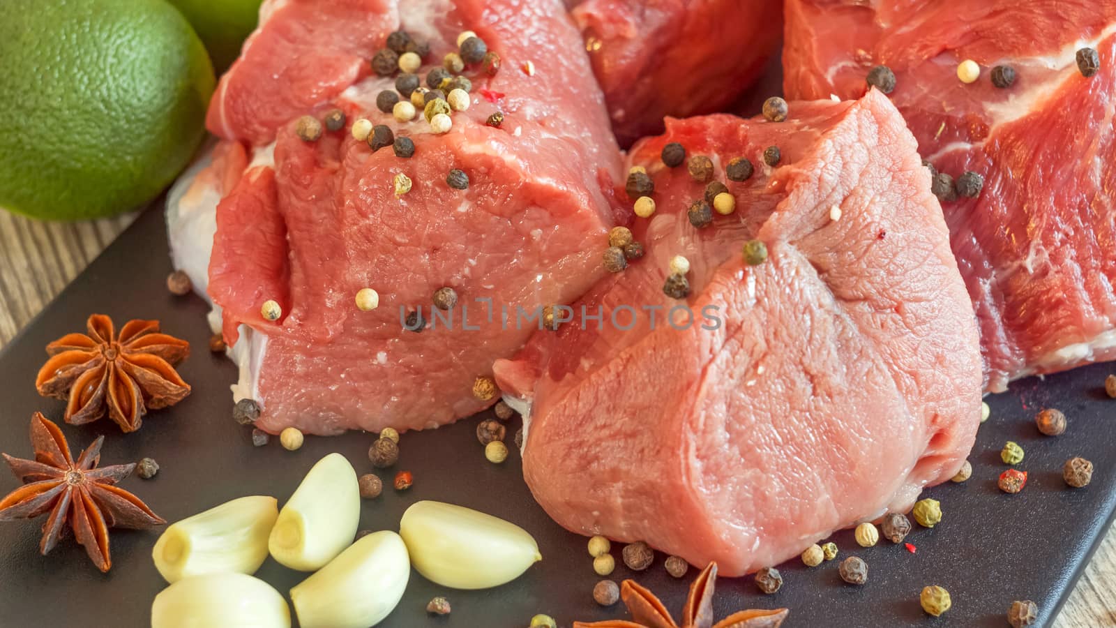 Cooking for lunch the fresh diet of red meat for gourmets. Red meat on a black Board sprinkled with pepper, garlic, anise and lime. Billets for BBQ, steak or shish kebabs