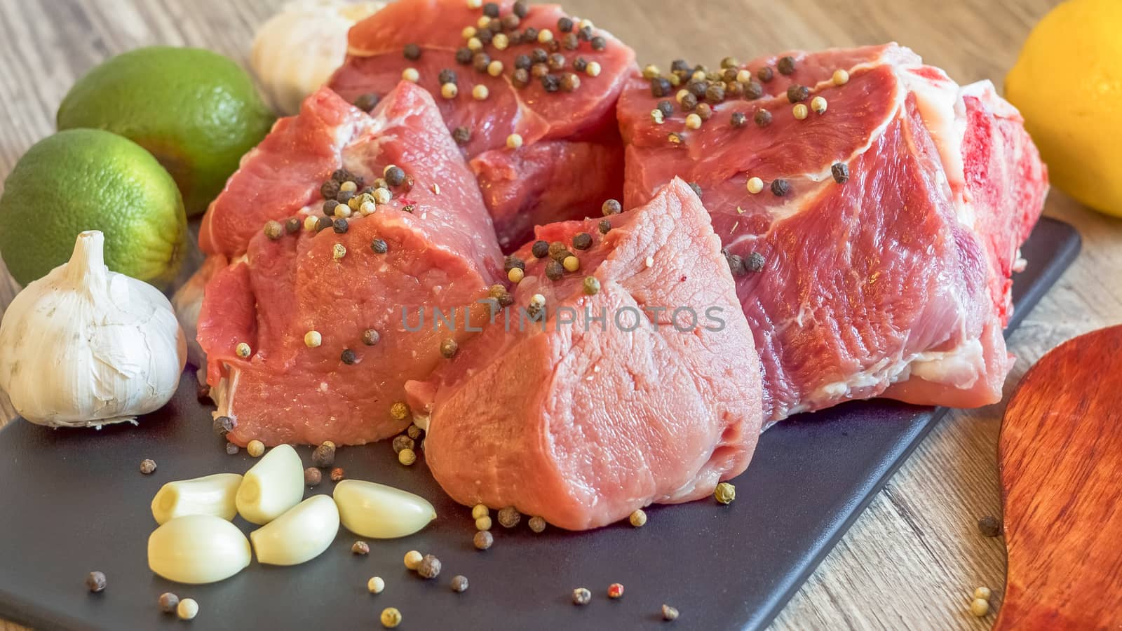 Cooking for lunch the fresh diet of red meat for gourmets. Red meat on a black Board sprinkled with pepper, garlic, anise and lime. Billets for barbecue,  steak or shish kebabs