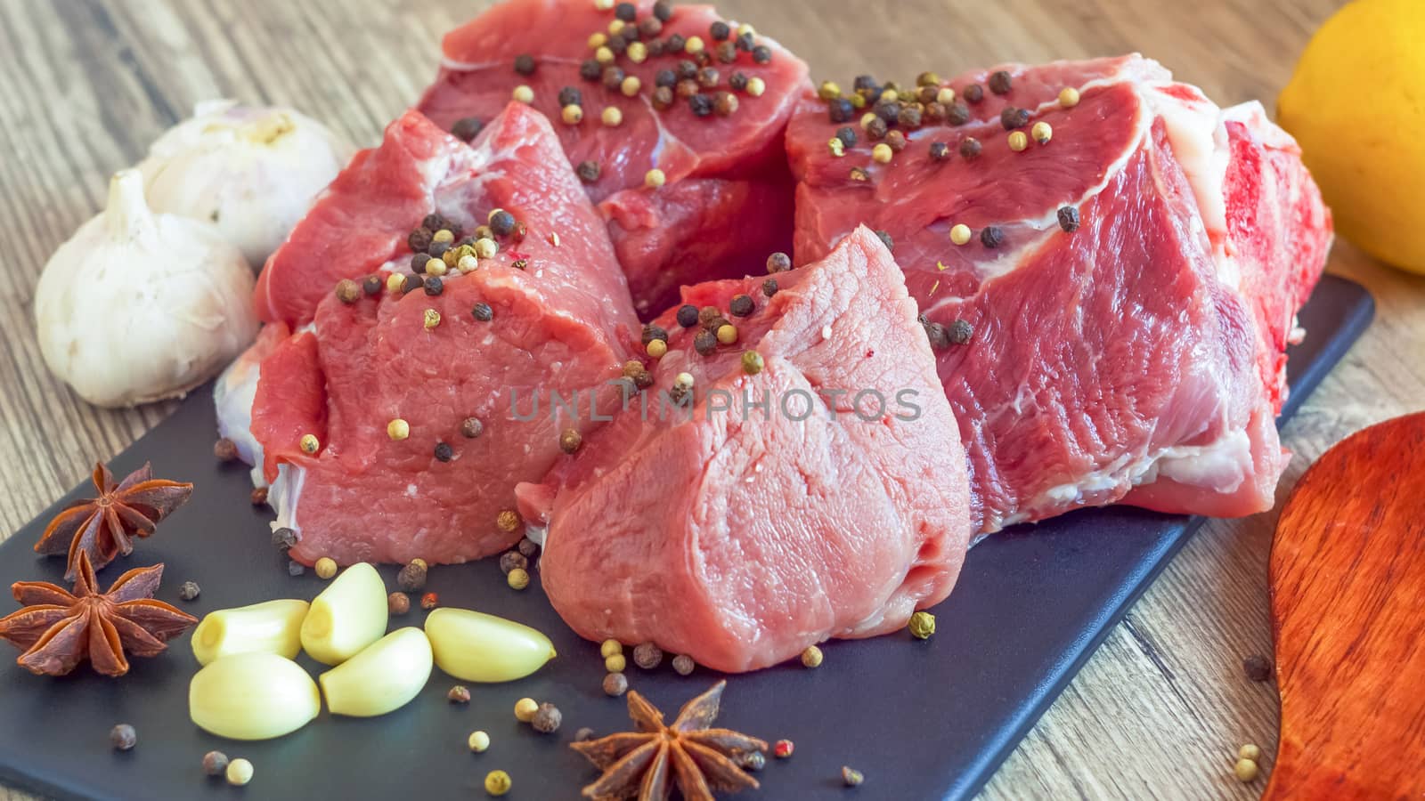 Red meat on a black Board sprinkled with pepper, garlic, anise and lime. Billets for barbecue,  steak or shish kebabs. Cooking for lunch the fresh diet of red meat for gourmets.