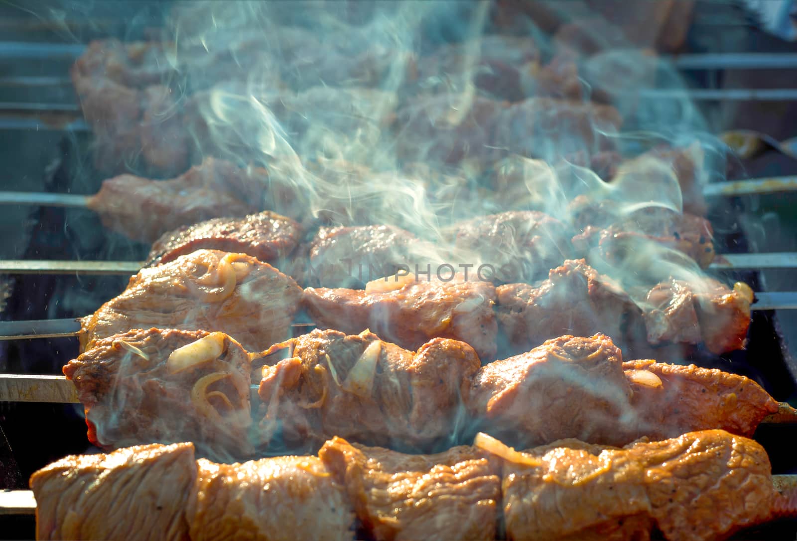 Meat on grill. Morning BBQ. Cooking barbecue on the grill with smoke. Cook fresh marinated meat with onions. Grill marinated barbecue is prepared on the grill on the coals