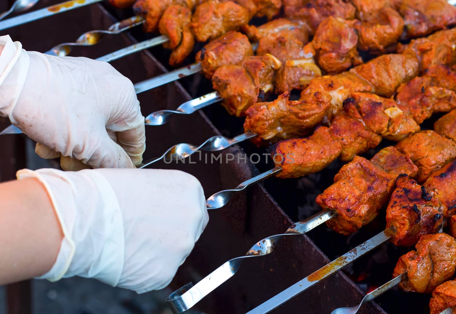 The chef is preparing a barbecue in gloves. We cook meat on the grill outdoors. BBQ