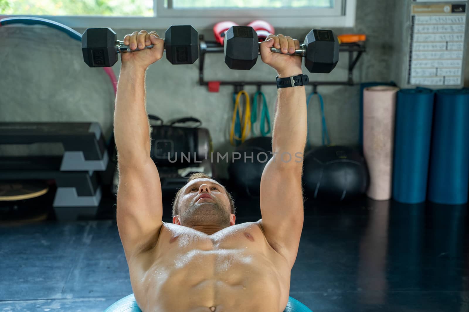 Men with dumbbells flexing muscles in gym,Fitness man training with heavy barbells in contemporary sports club.