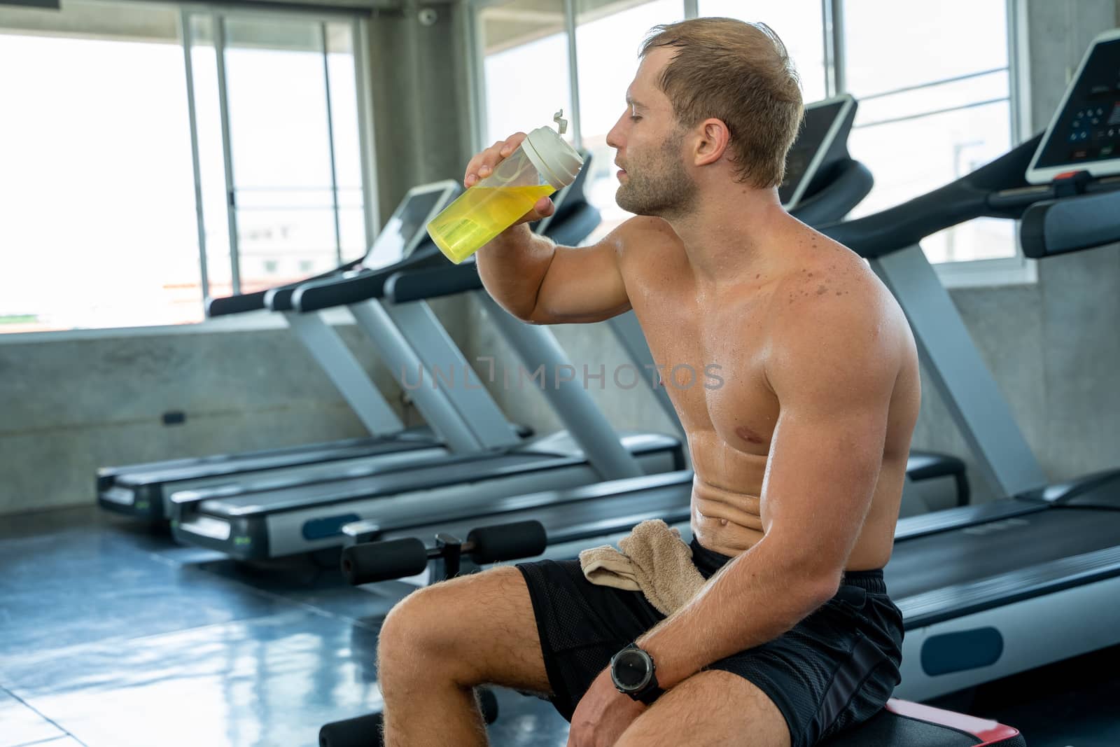 Fitness man raise water bottles and drink after exercising in gym,Man having a break drinking a bottle of water.