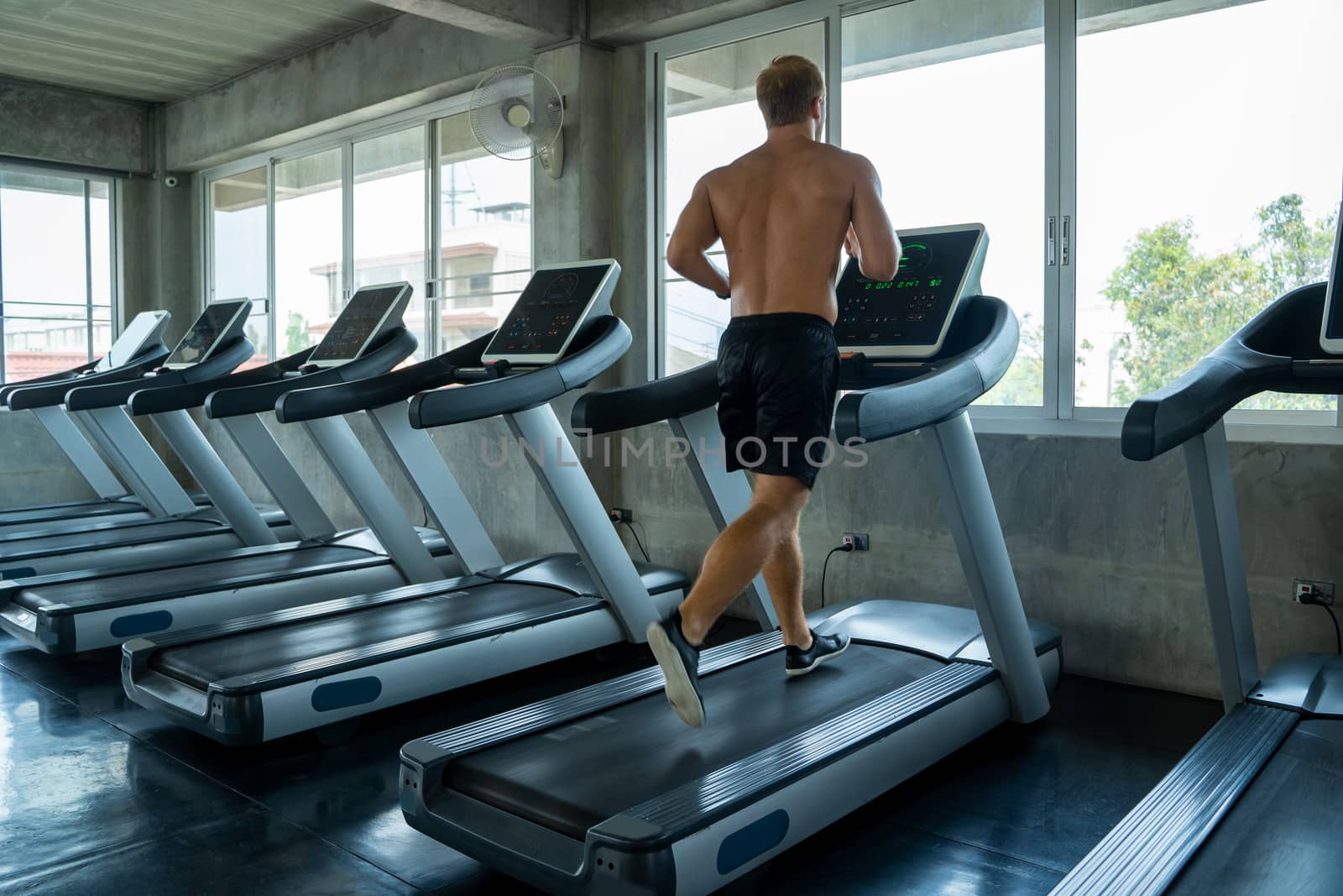 Fitness man are running on modern electric treadmills at the gym by Visoot