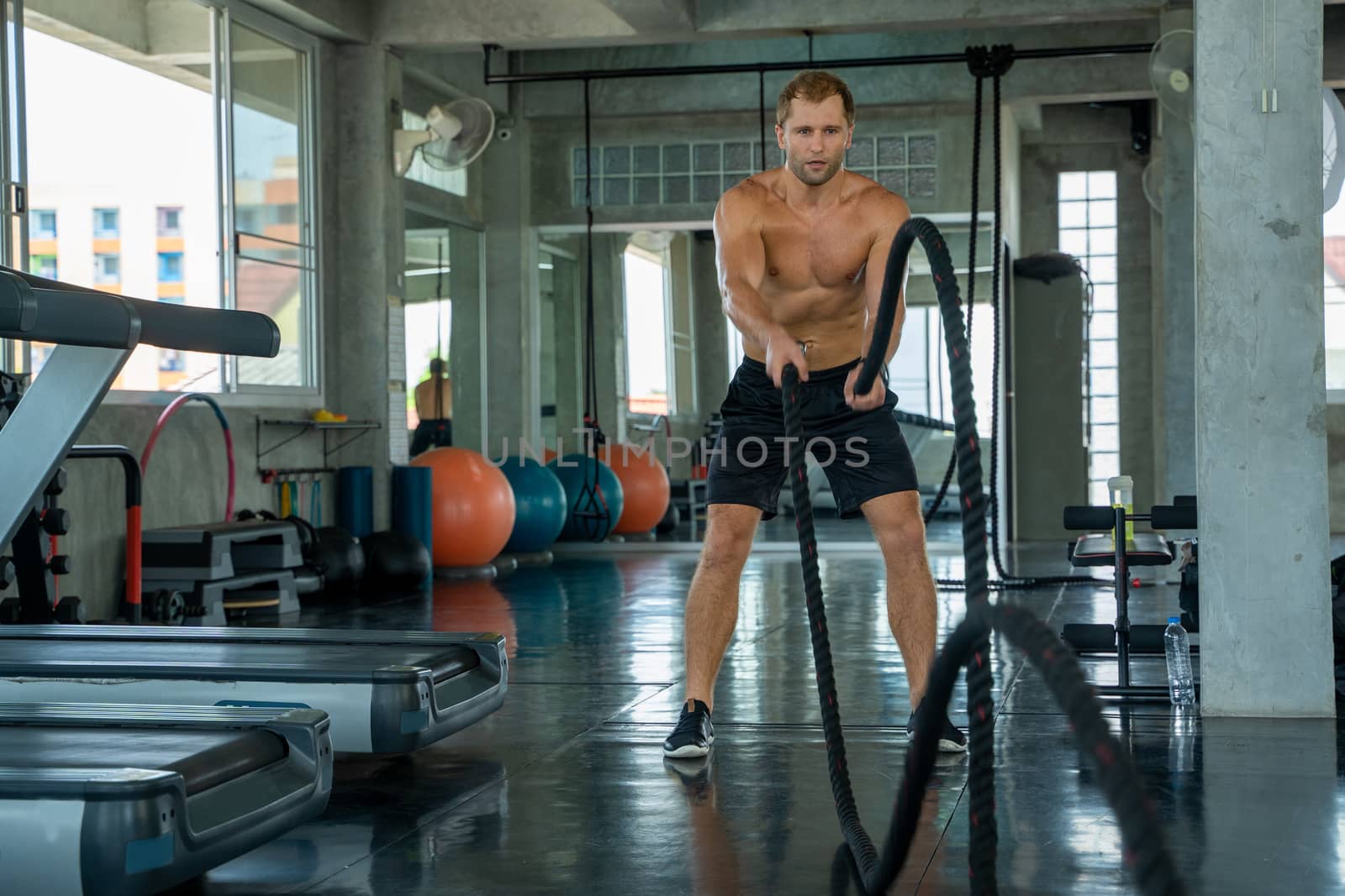 Strong man exercising with battle ropes at the gym,Training with by Visoot