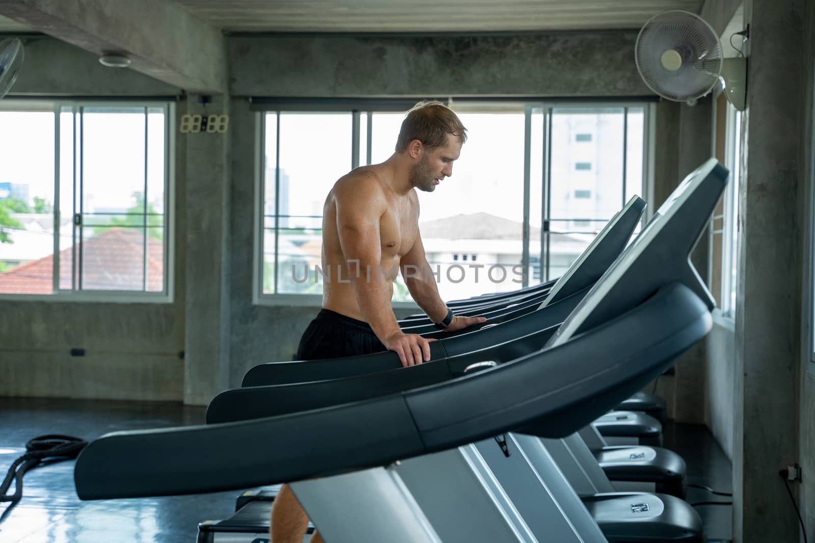 Fitness man running on modern electric treadmills at the gym. by Visoot