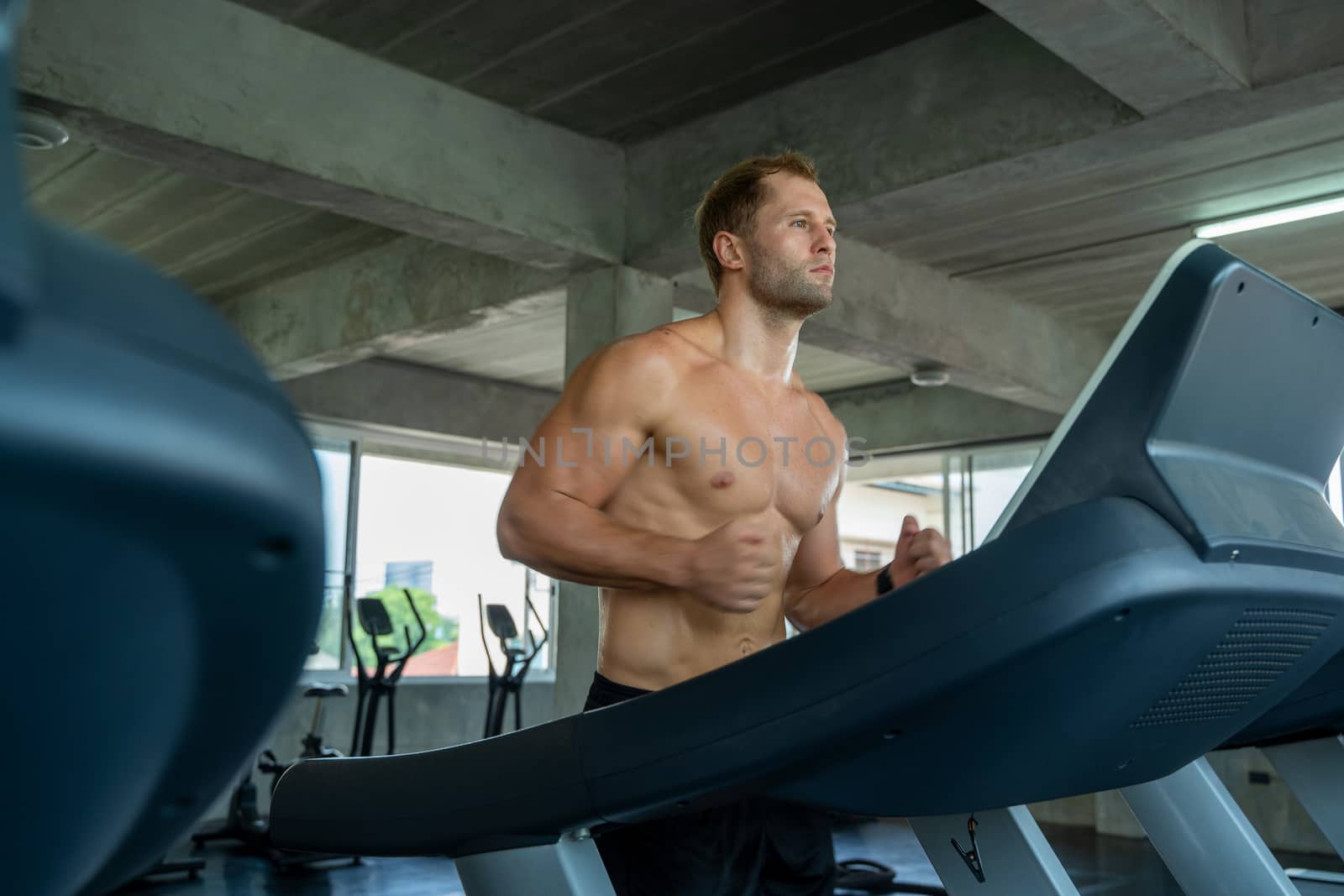 Fitness man are running on modern electric treadmills at the gym by Visoot