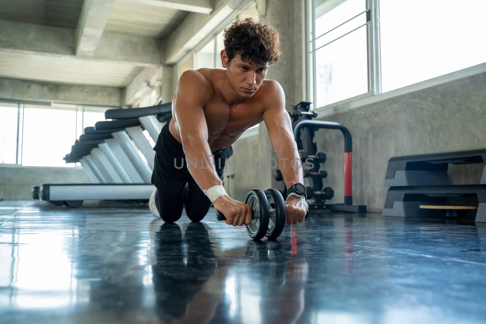 Athletic man exercising with fitness roller in gym club,Athlete builder muscles concept.