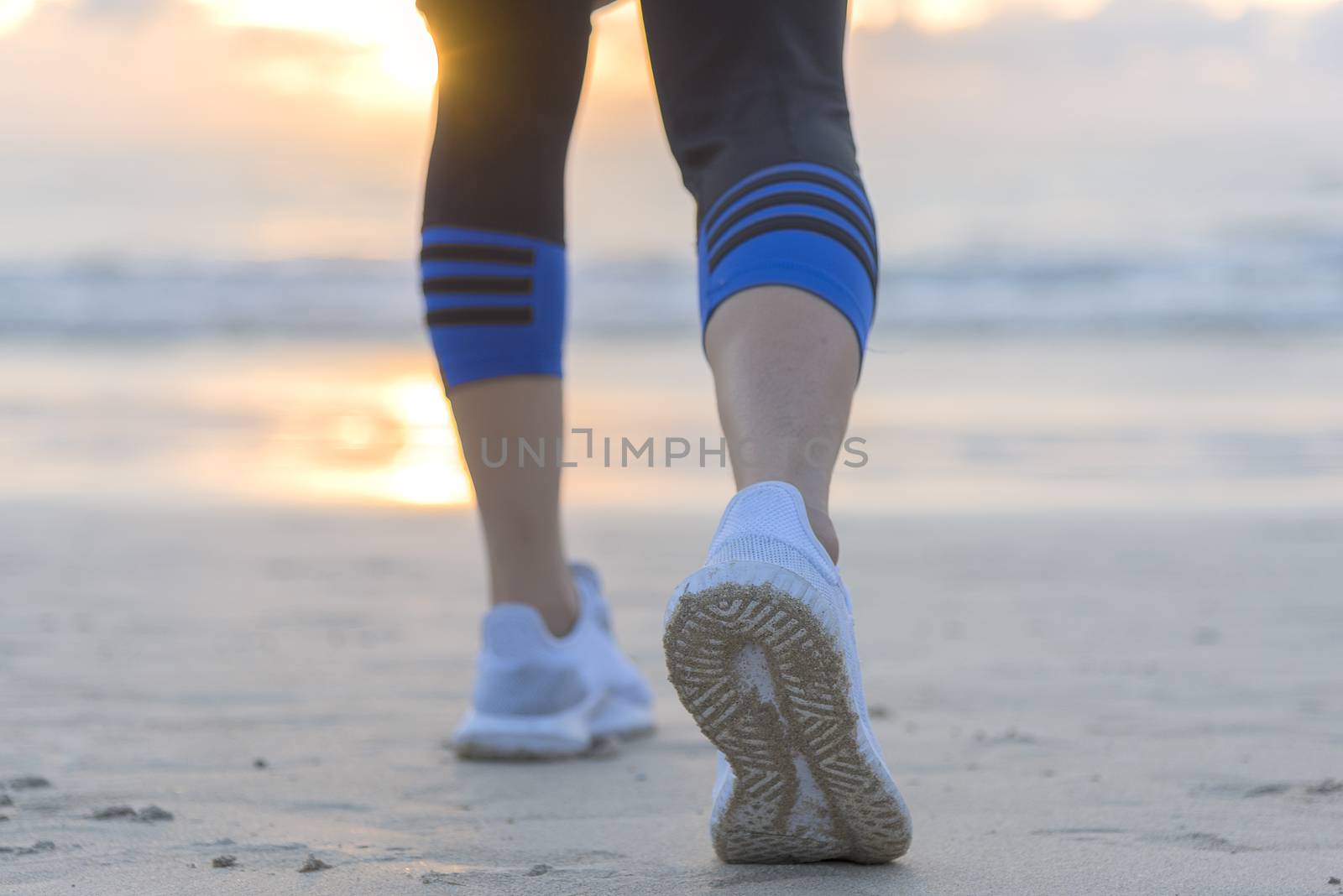 Woman running on the beach at sunrise closeup on shoe. Patong beach, Phuket, Thailand