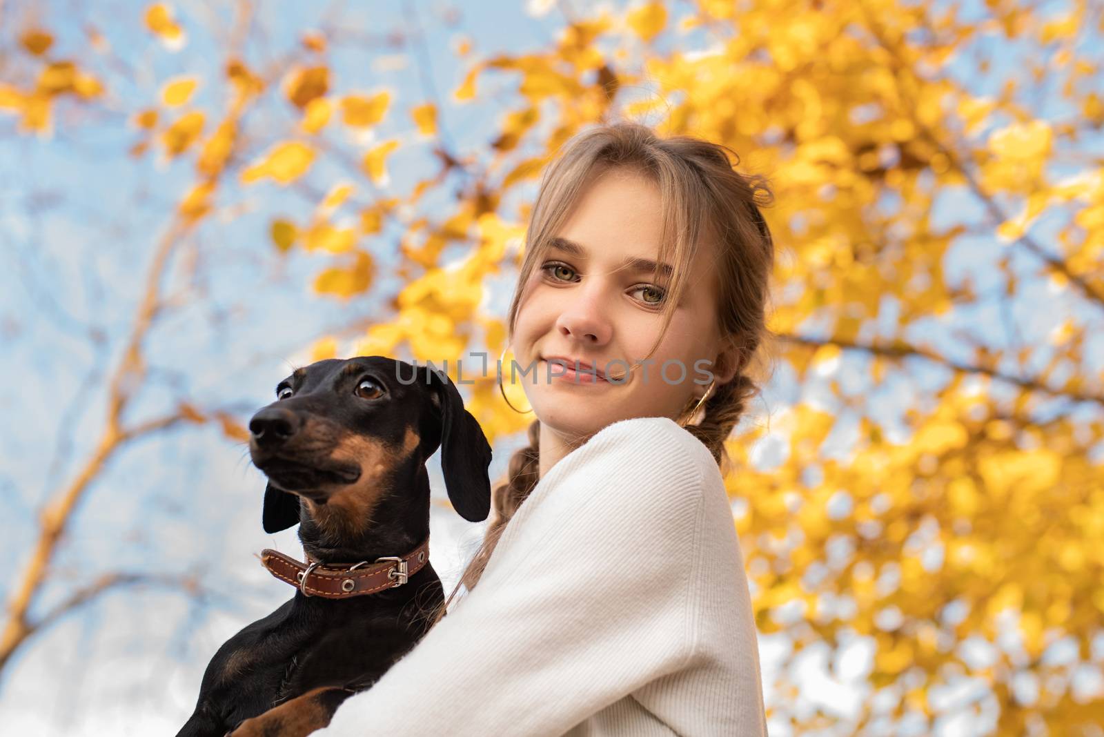 teenager girl holding her dachshund dog in her arms outdoors by Desperada