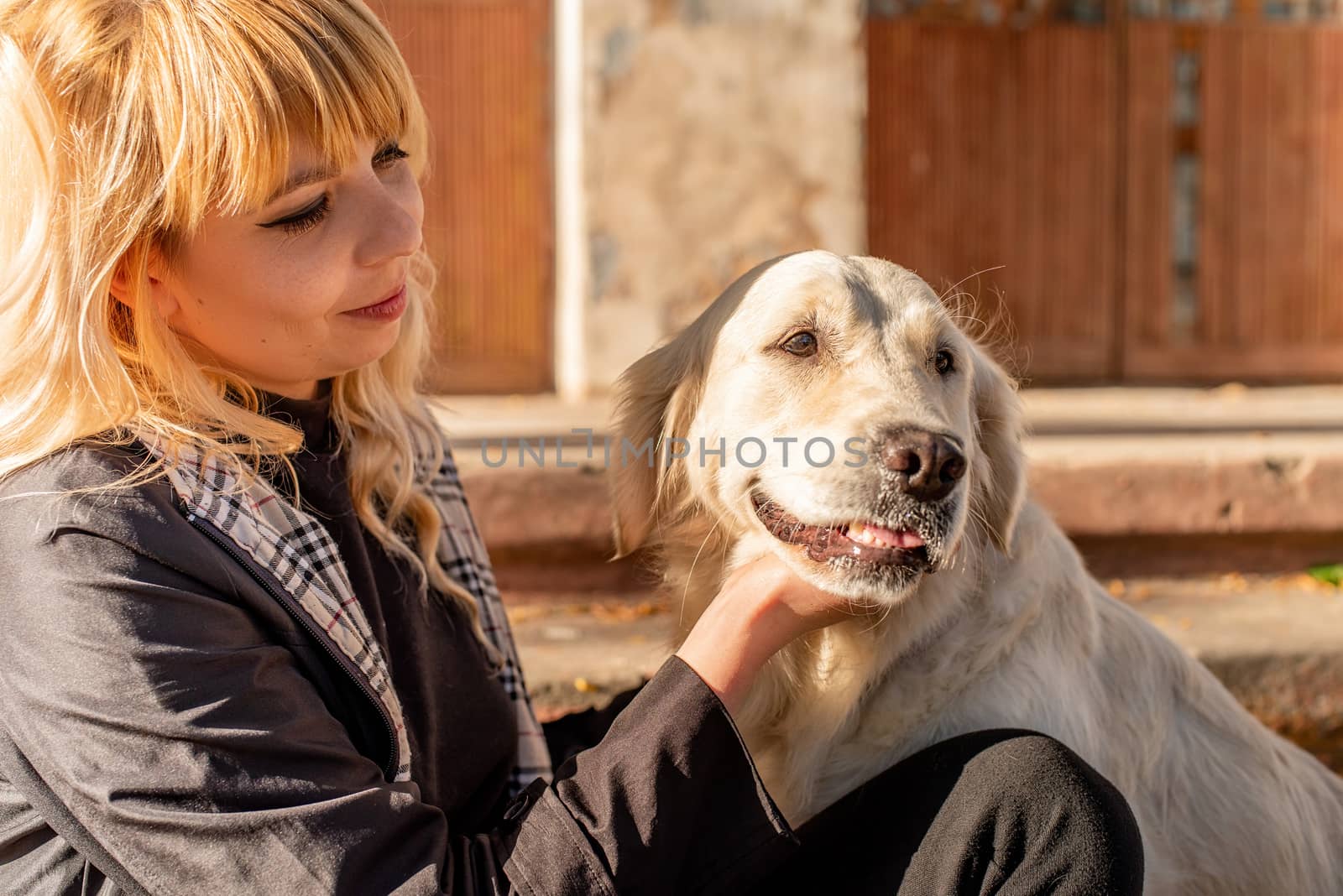 Pet care concept. Young smilingwith her golden retriever dog outdoors