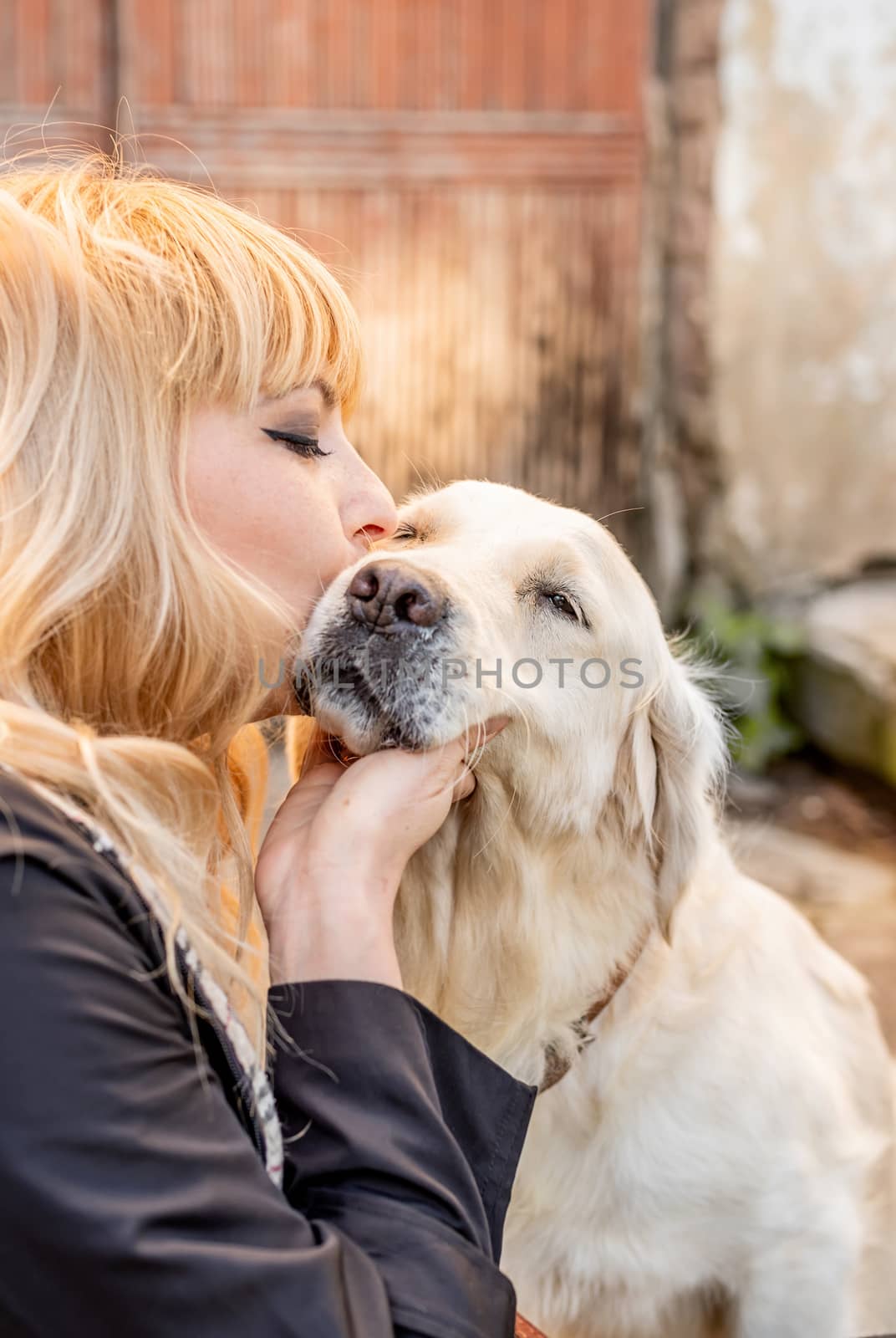 blond woman kissing her retriever dog by Desperada