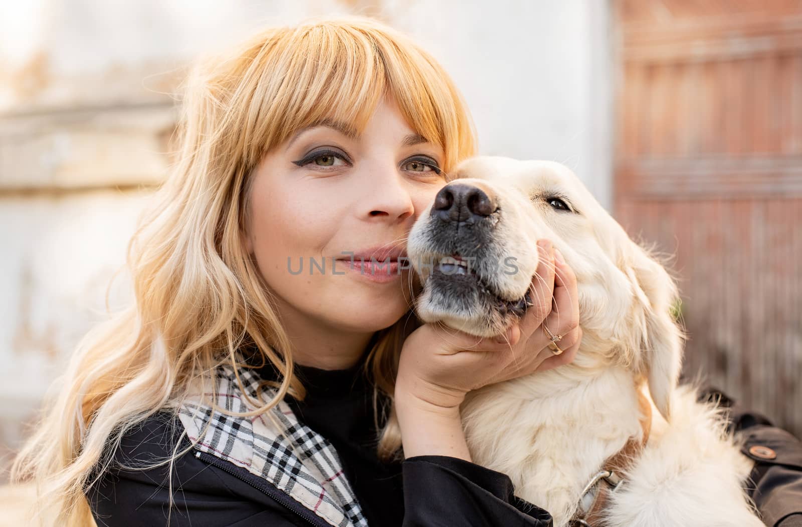 Pet care concept. Blond caucasian woman hugging her golden retriever dog outdoors