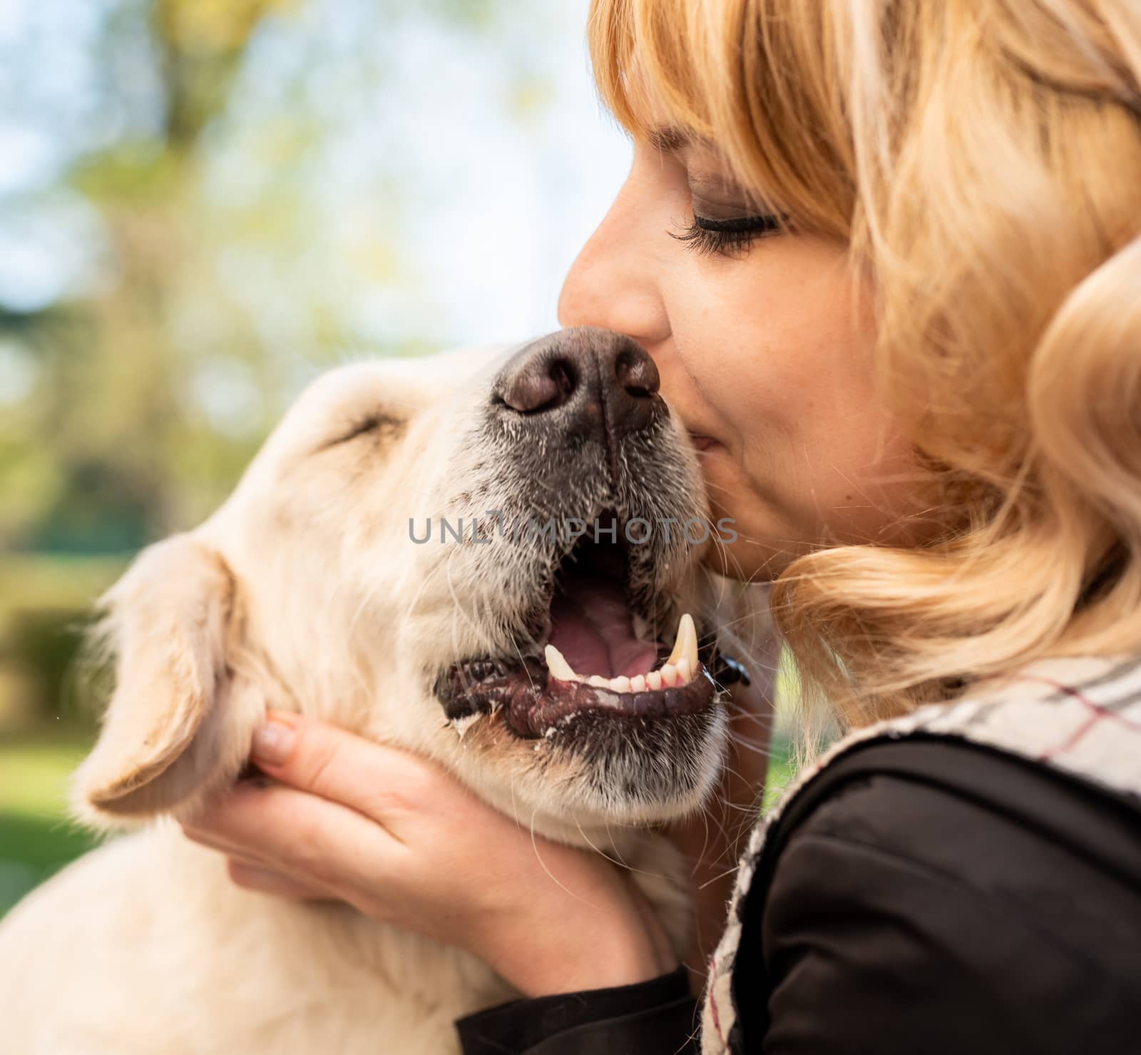 Pet care concept. Blond caucasian woman hugging her golden retriever dog outdoors