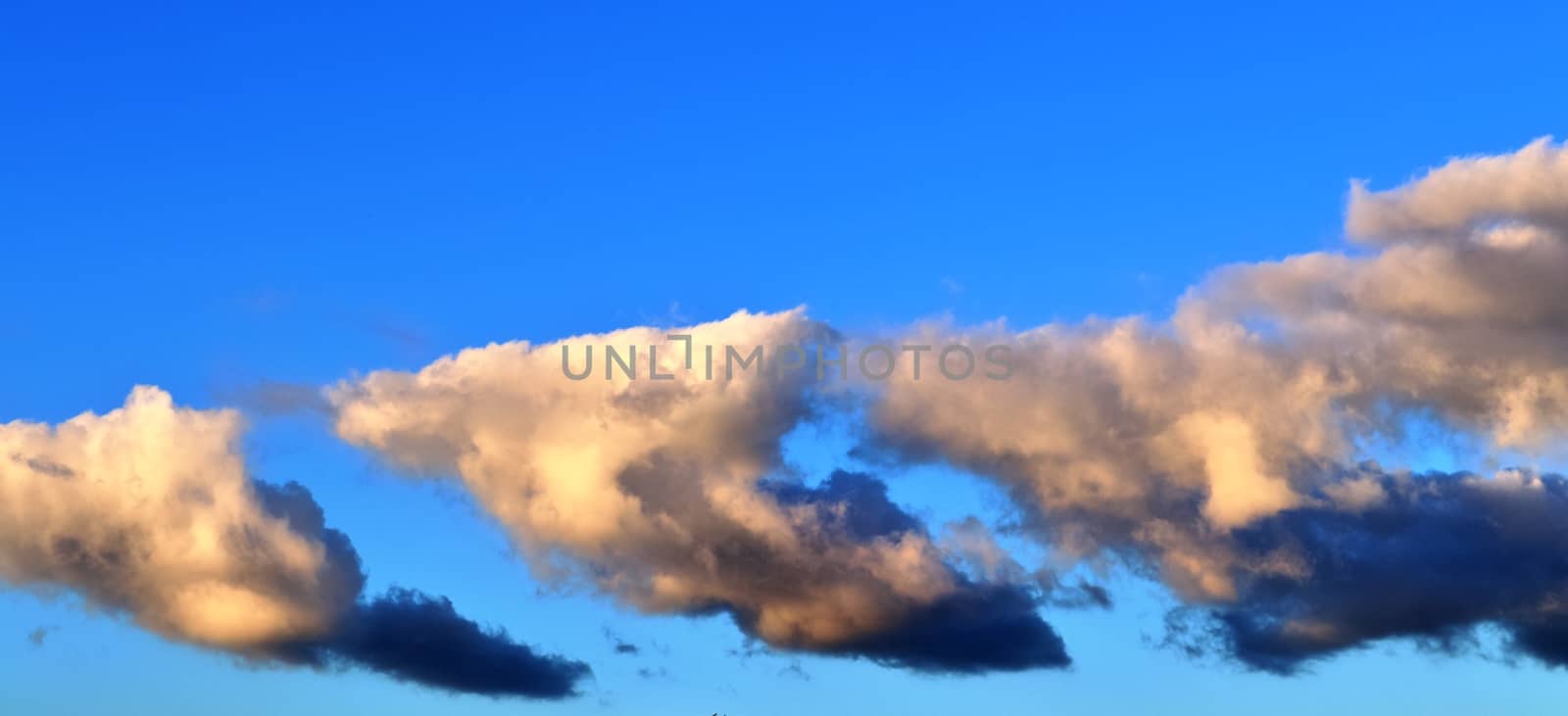 Beautiful panorama of orange and yellow clouds at sunrise and sunset in a blue sky