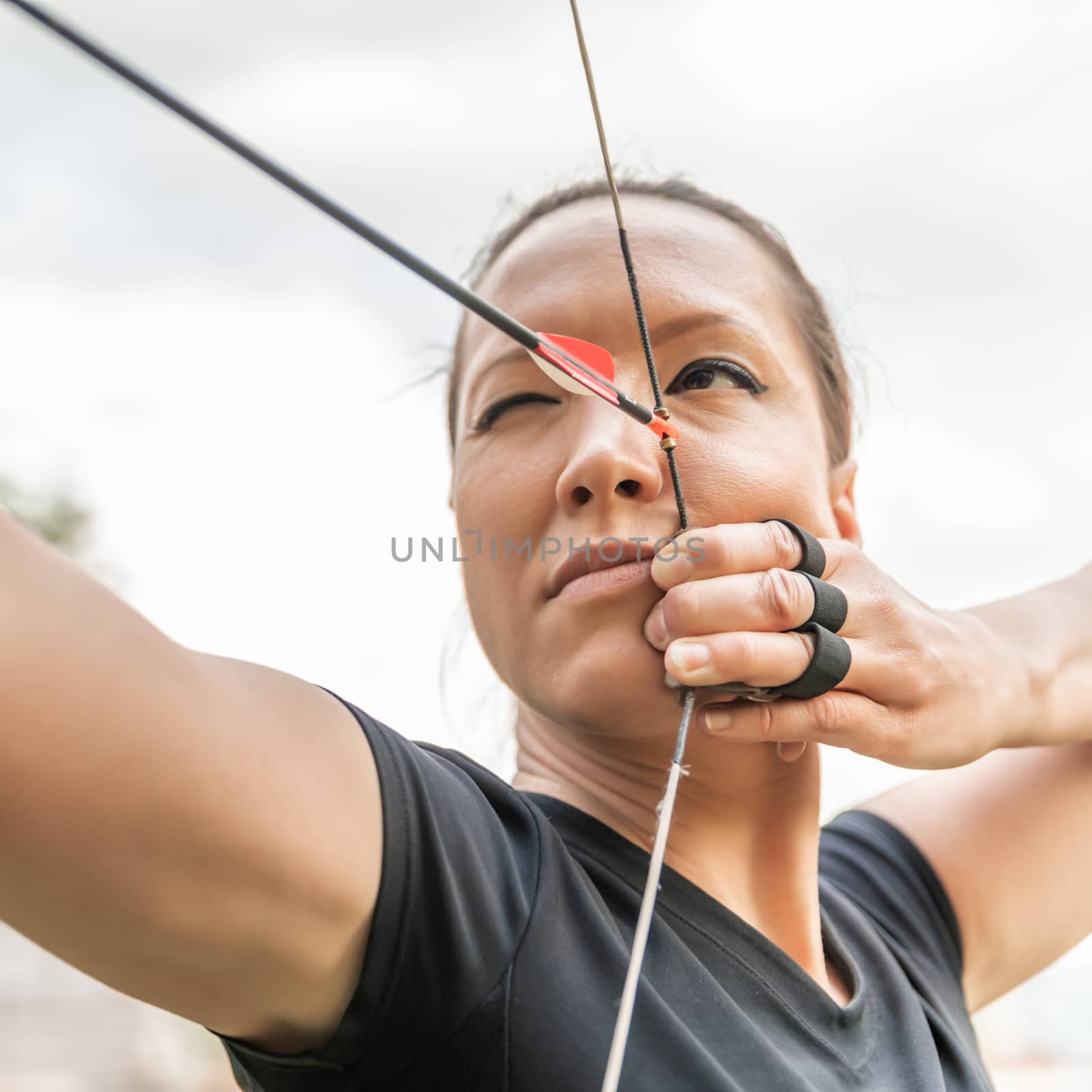 attractive woman on archery, focuses eye target for arrow from bow.