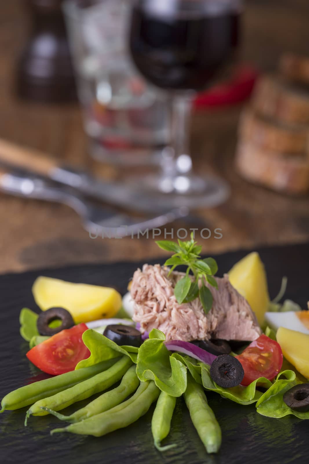 salad nicoise on a wooden background by bernjuer