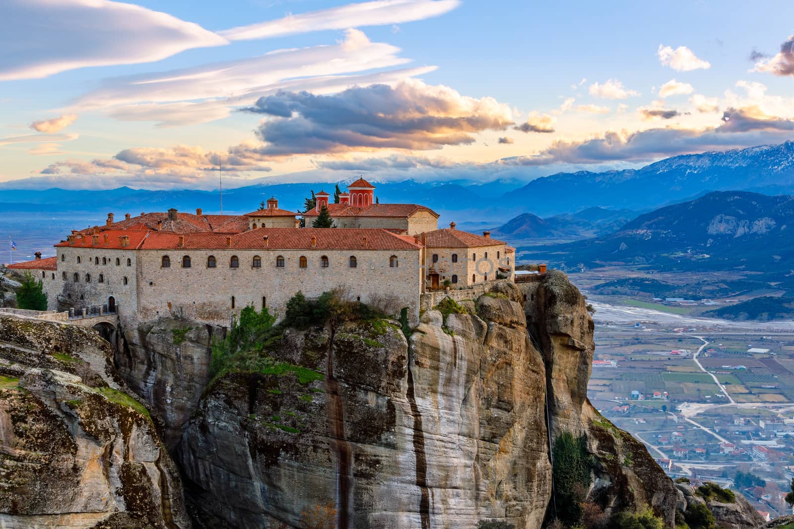 Agios Stephanos or Saint Stephen monastery located on the huge rock with mountains and town landscape in the background, Meteors, Trikala, Thessaly, Greece