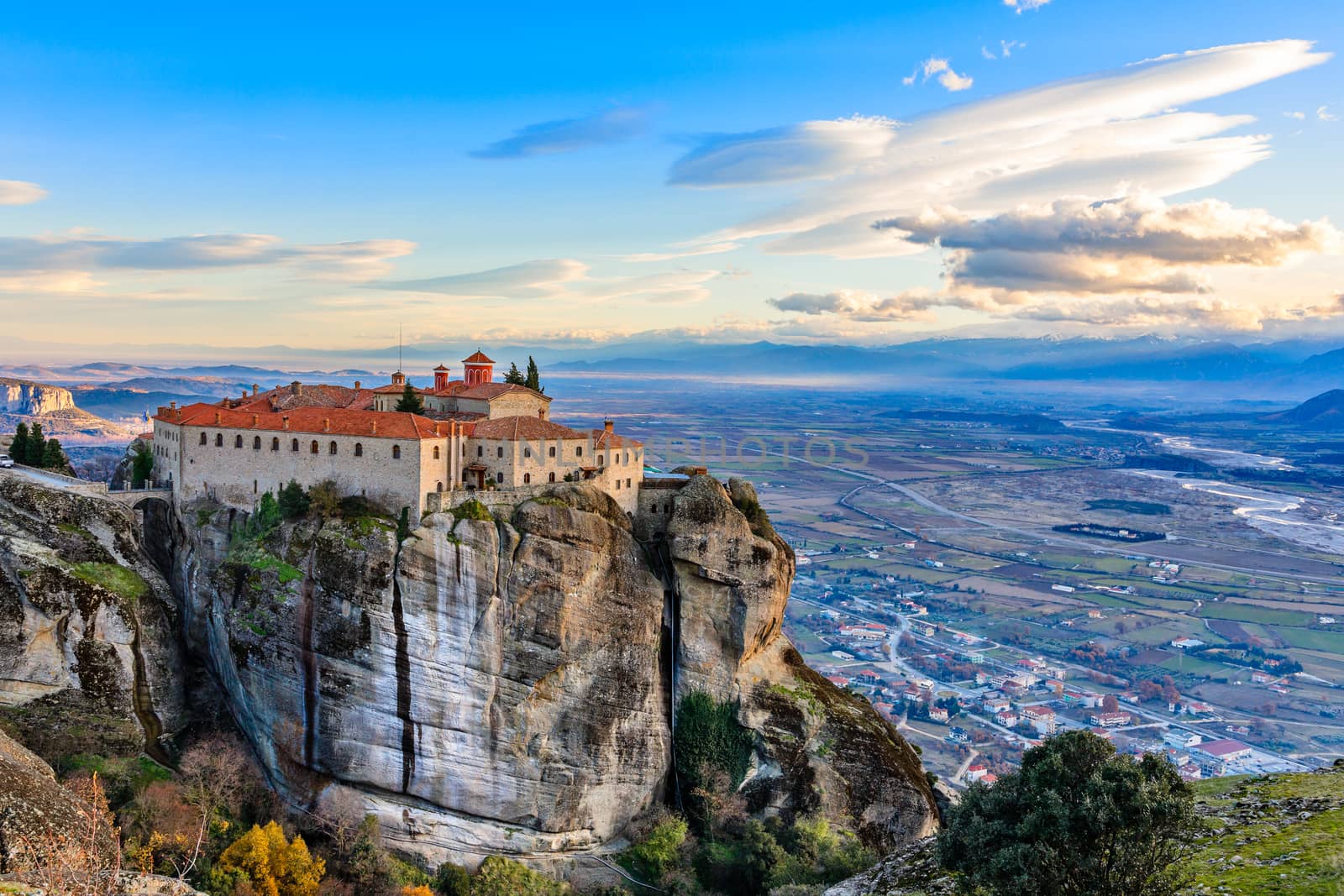 Agios Stephanos or Saint Stephen monastery located on the huge rock with mountains and town landscape in the background, Meteors, Trikala, Thessaly, Greece