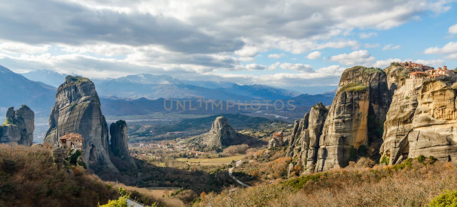 Four monasteries of Meteors: Roussanou, Monastery of Agios Nikolaos Anapafsas, Varlaam and Grand Meteora scattered on the steep cliffs with mountains panorama and Kastraki village in background, Kalampaka, Trikala, Thessaly, Greece