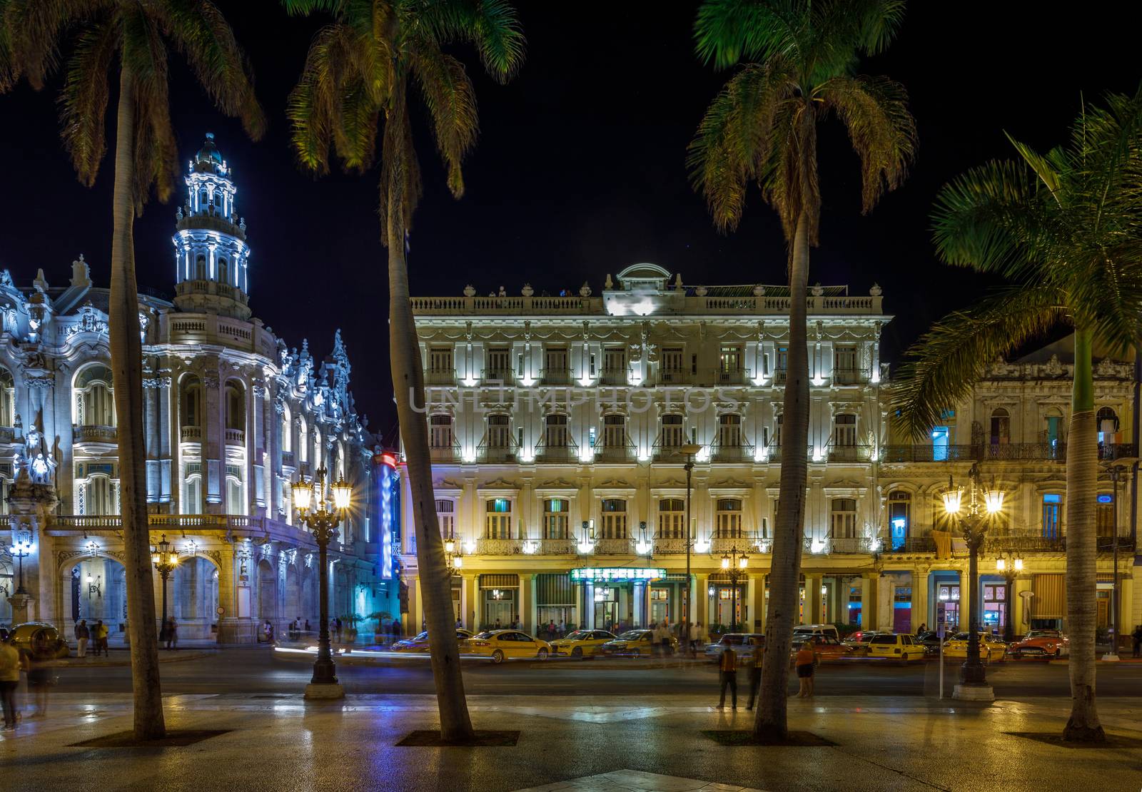 Night Cuban street with palms, road, taxi and old shining hispanic colonial buildings, center of Havana, Cuba