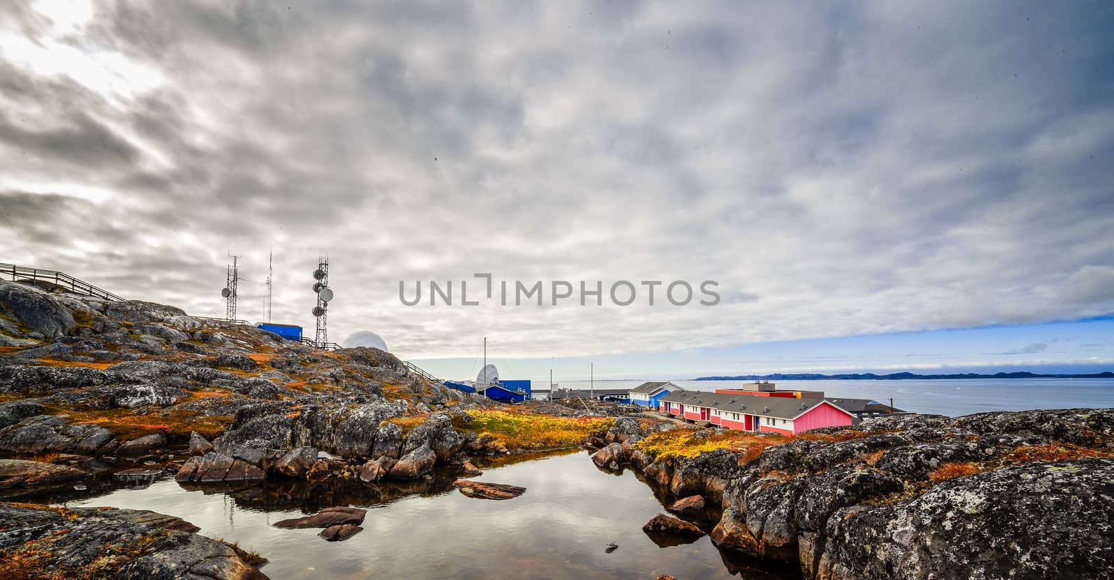 Rocks, lake, living houses and radio tower in the background in a suburb of Nuuk city, Greenland