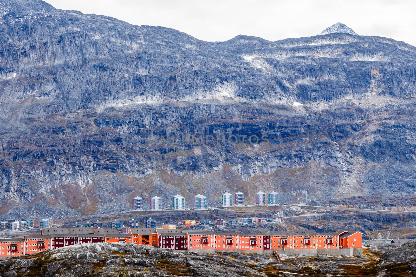 Rows of colorful modern Inuit houses among mossy stones with grey steep slopes of Little Malene mountain in the background, Nuuk, Greenland