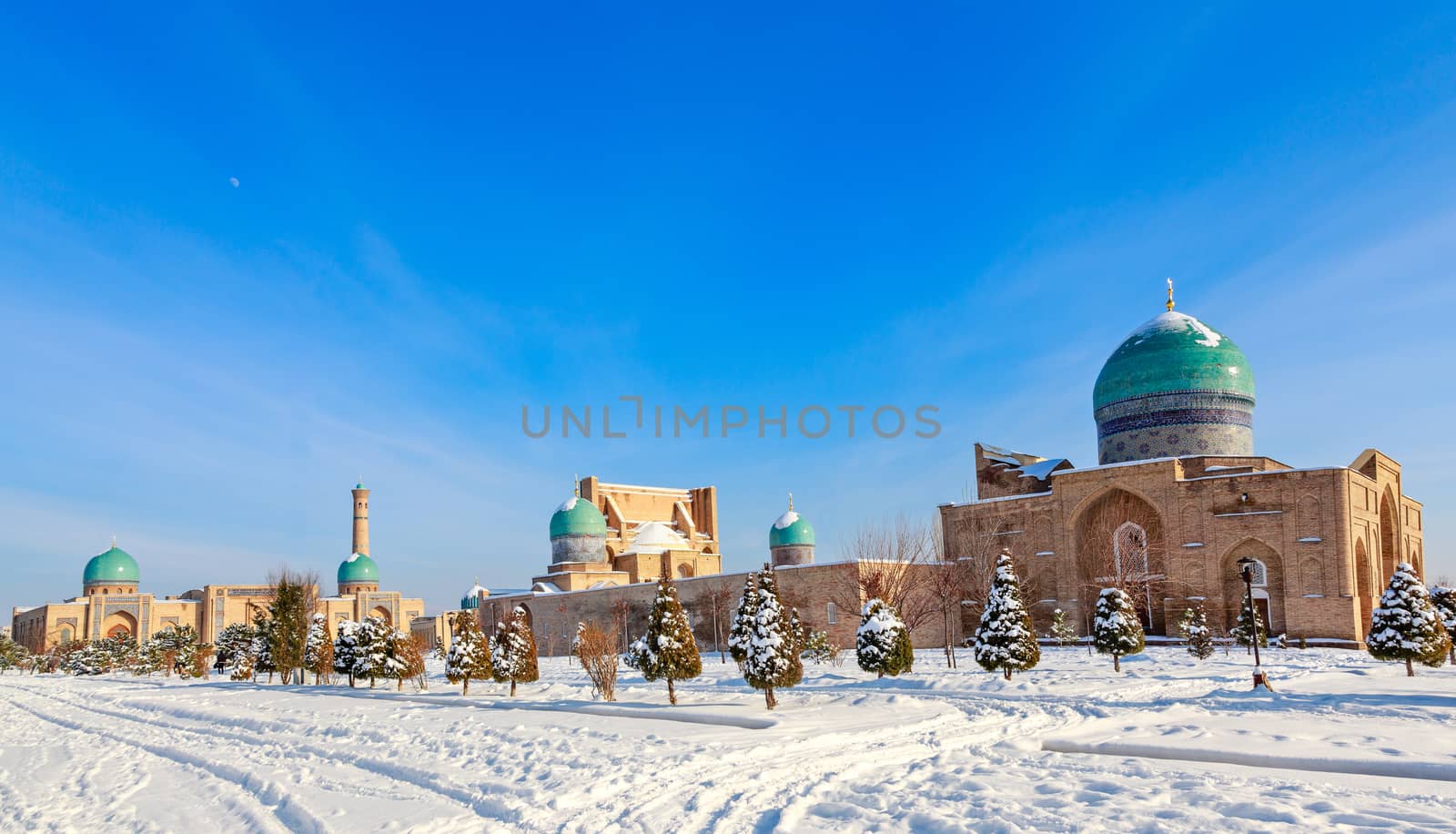 Snow and spruces with blue domes and minarets of muslim Hazrati Imam complex, religious center of Tashkent, Uzbekistan