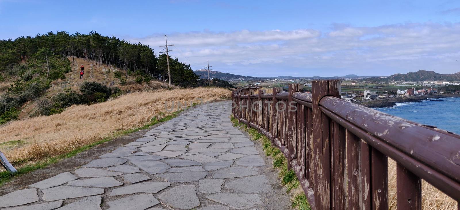 A paved path on the songaksan mountain with fence in Jeju Island, South Korea