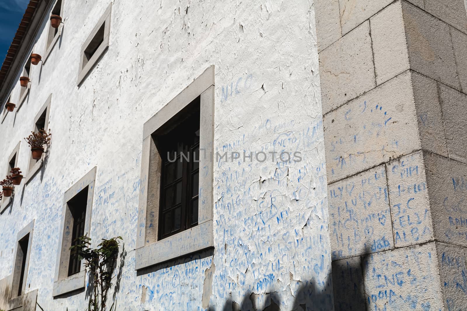 Obidos, Portugal - April 12, 2019: Wall covered with blue signatures in the historic city center on a spring day