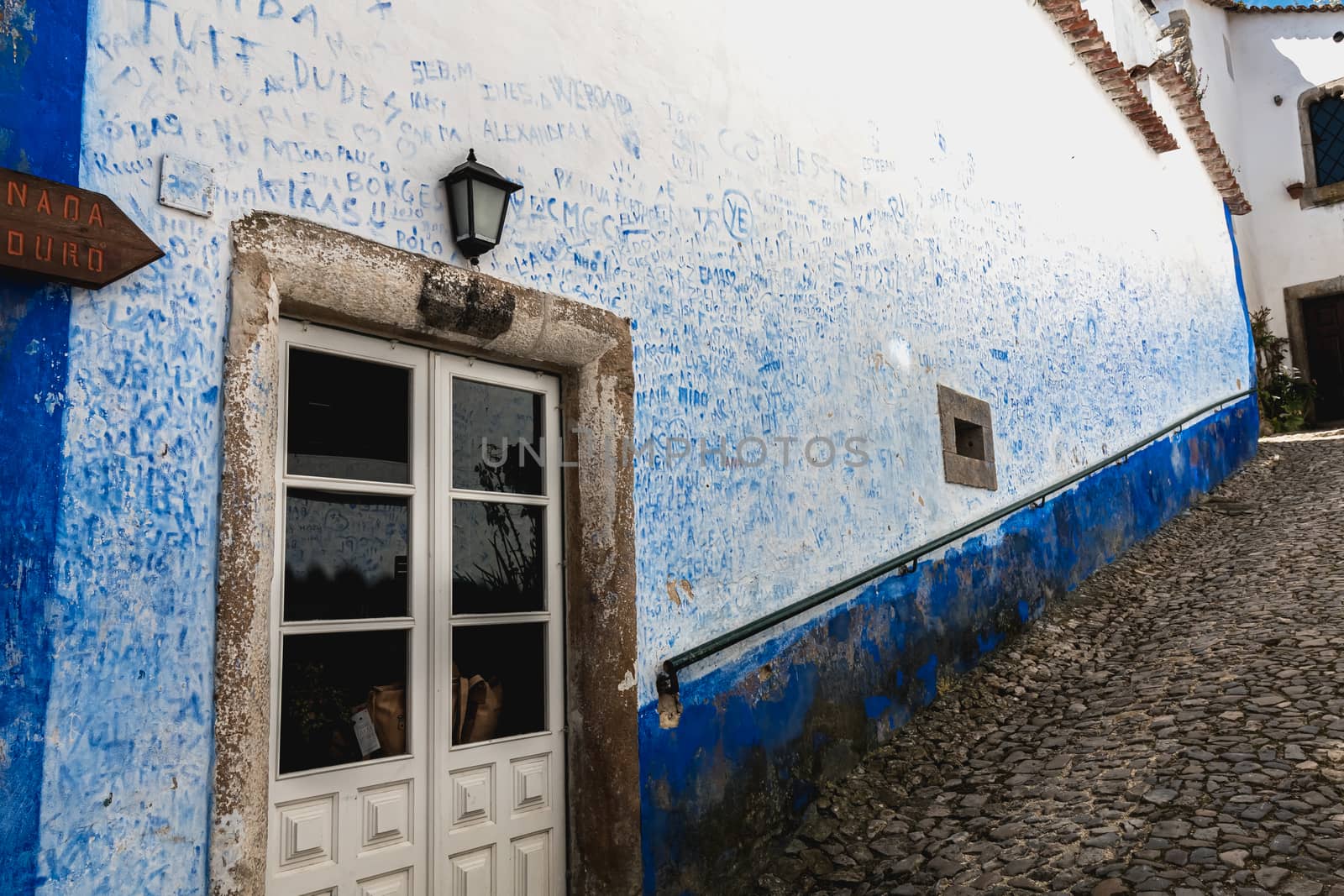 Obidos, Portugal - April 12, 2019: Wall covered with blue signatures in the historic city center on a spring day