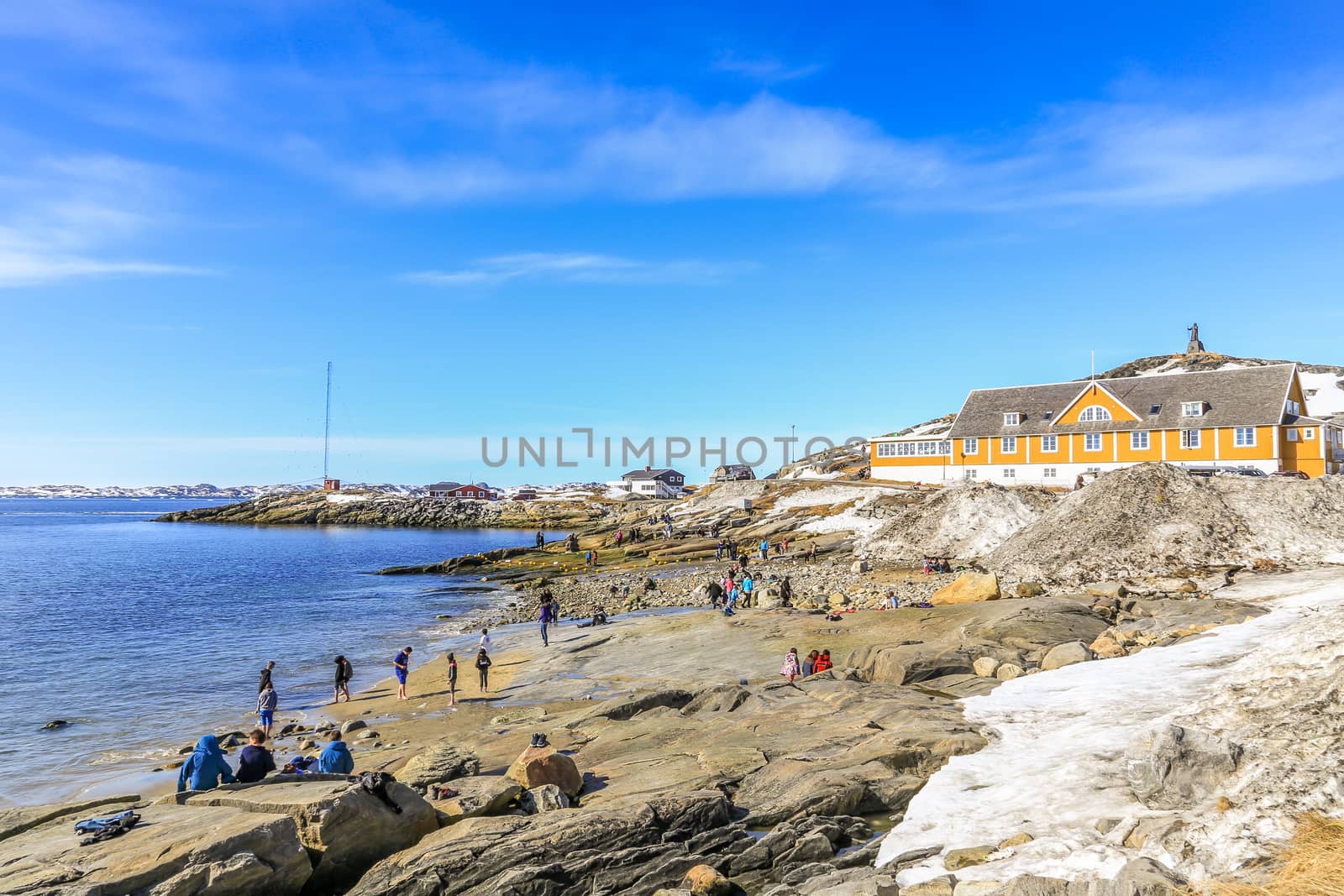 Beach time for Inuit people enjoying the sunny May day at the sea fjord, Nuuk city, Greenland