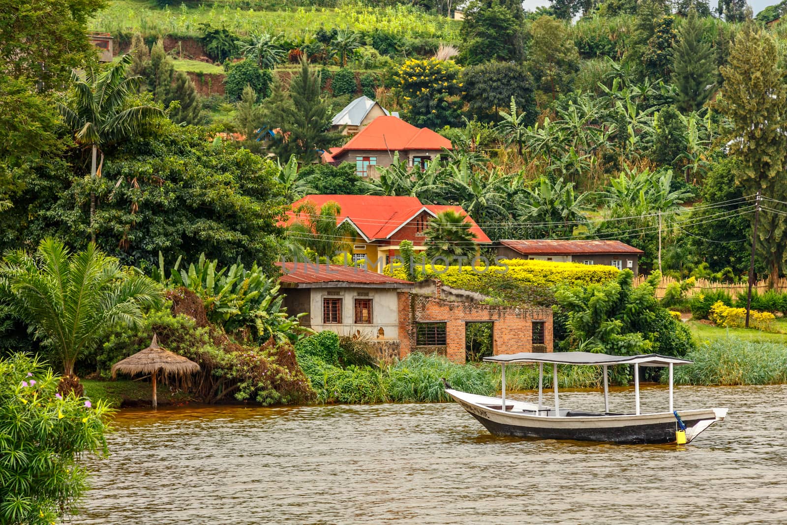 Roof boat anchored at the coast with rwandan village in the background, Kivu lake, Rwanda