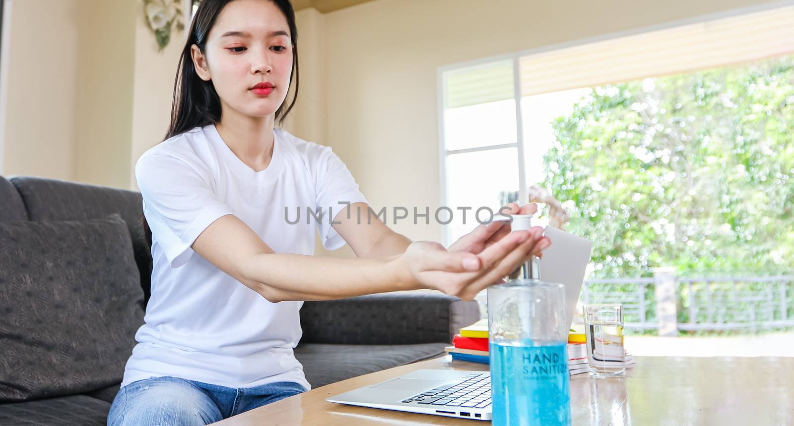Asian Business woman working from home and she is Cleaning her hands with sanitizer gel for protective coronavirus .She is quarantined at home during the coronavirus epidemic.
