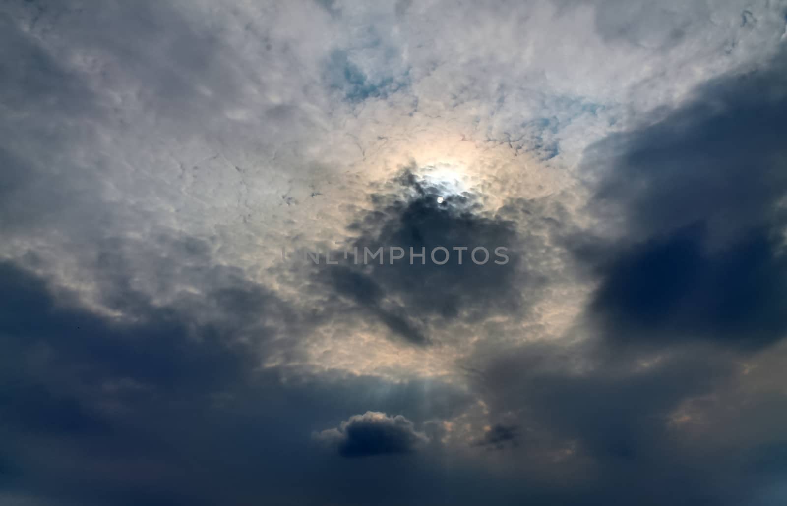 Beautiful view at bright sunbeams with some lens flares and clouds in a blue sky