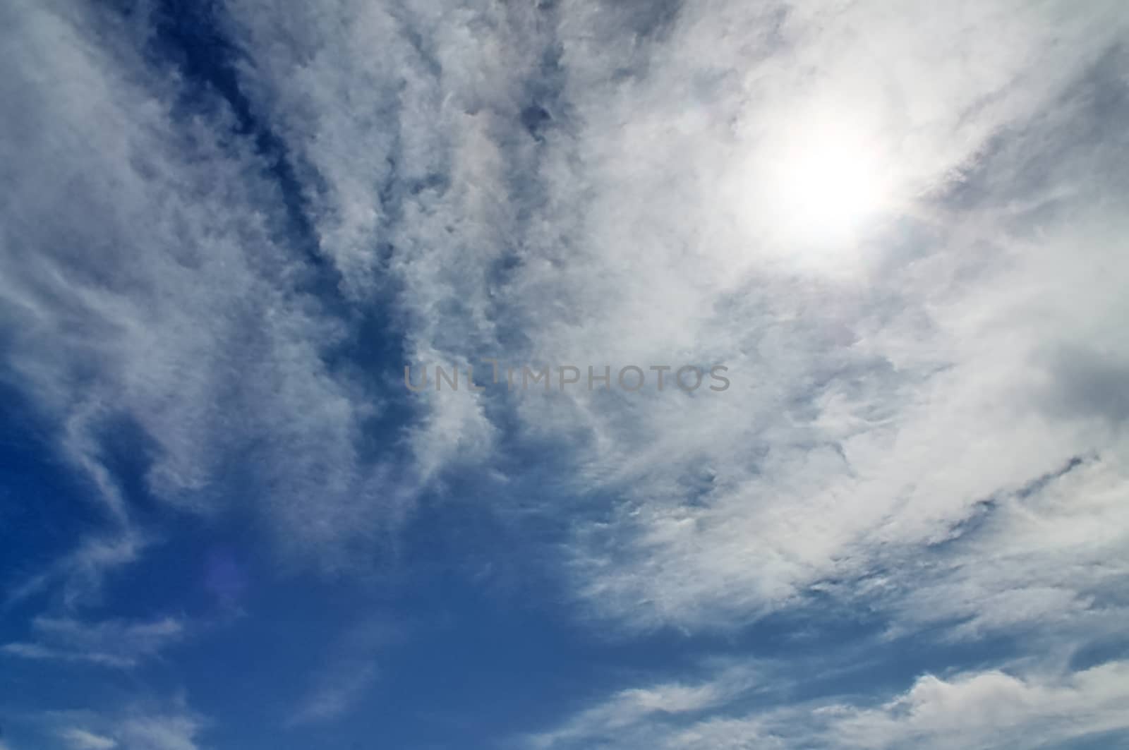 Beautiful view at bright sunbeams with some lens flares and clouds in a blue sky