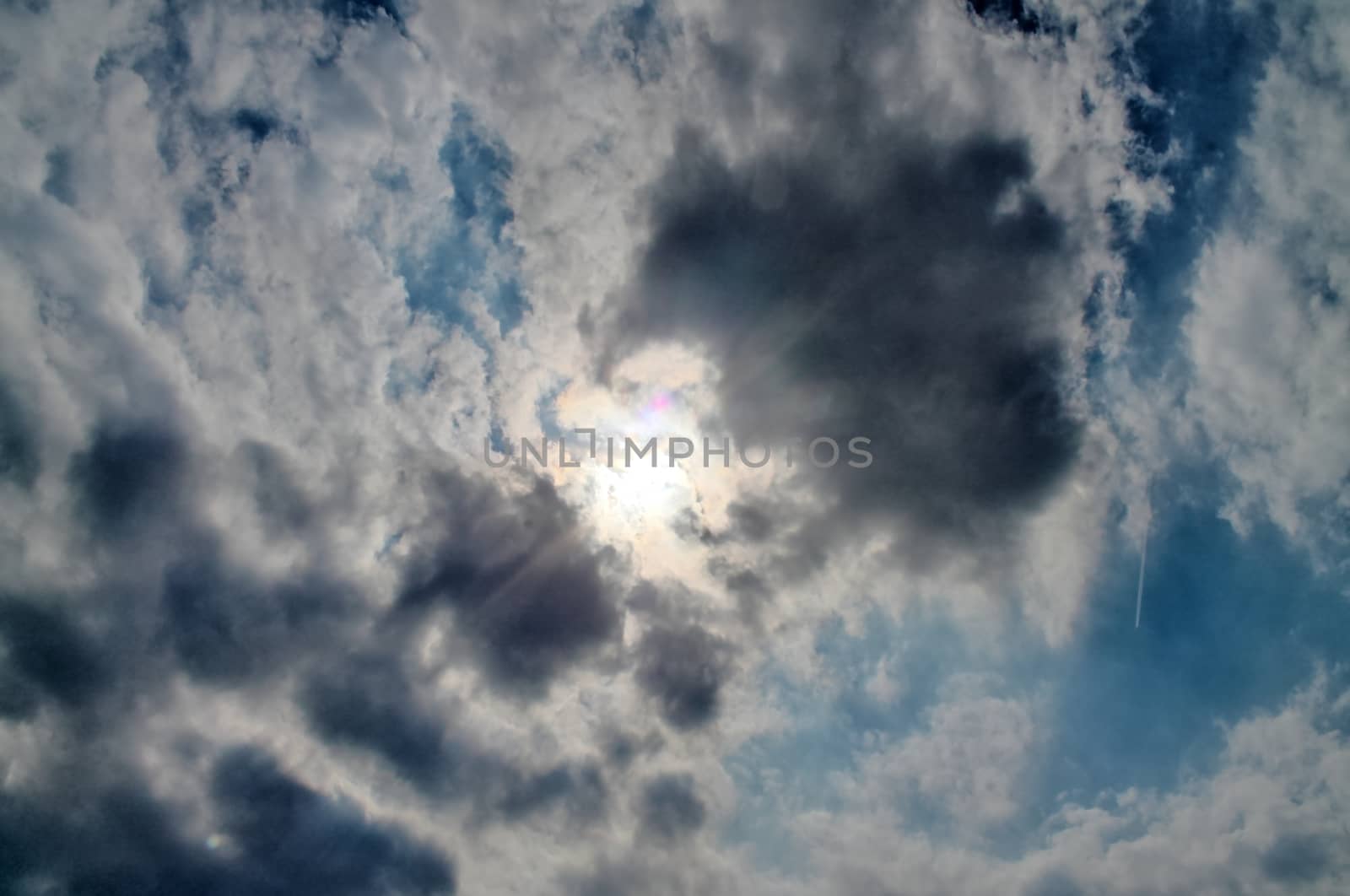 Beautiful view at bright sunbeams with some lens flares and clouds in a blue sky