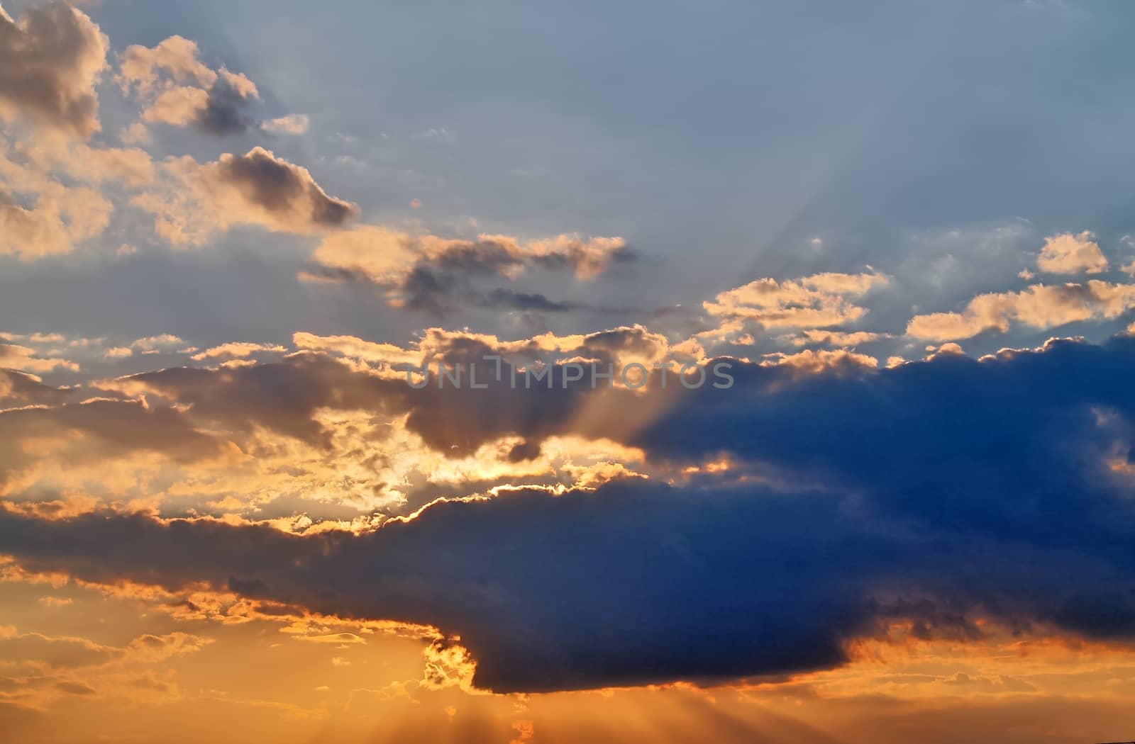 Beautiful view at bright sunbeams with some lens flares and clouds in a blue sky