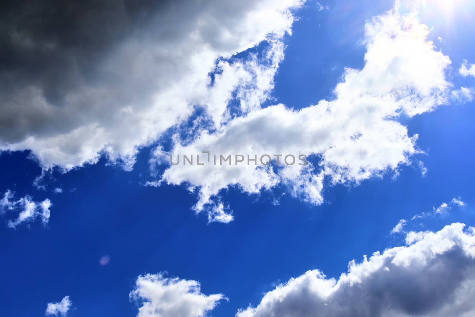 Beautiful view at bright sunbeams with some lens flares and clouds in a blue sky