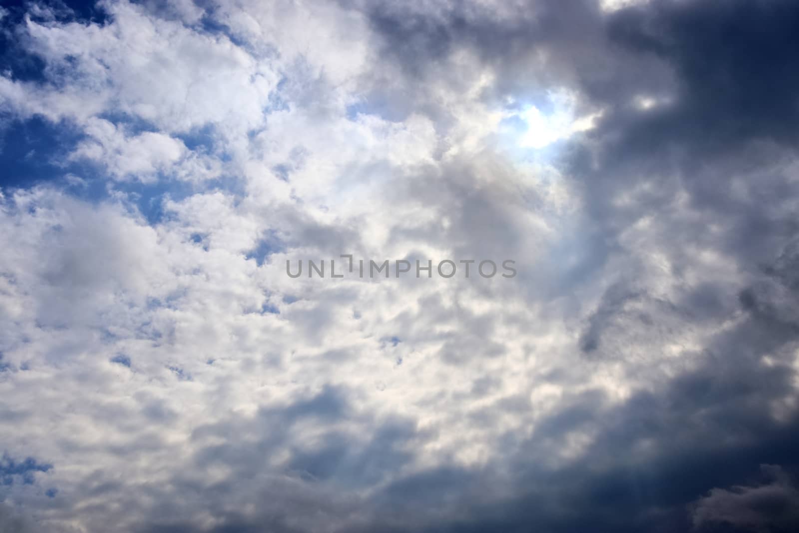 Beautiful view at bright sunbeams with some lens flares and clouds in a blue sky