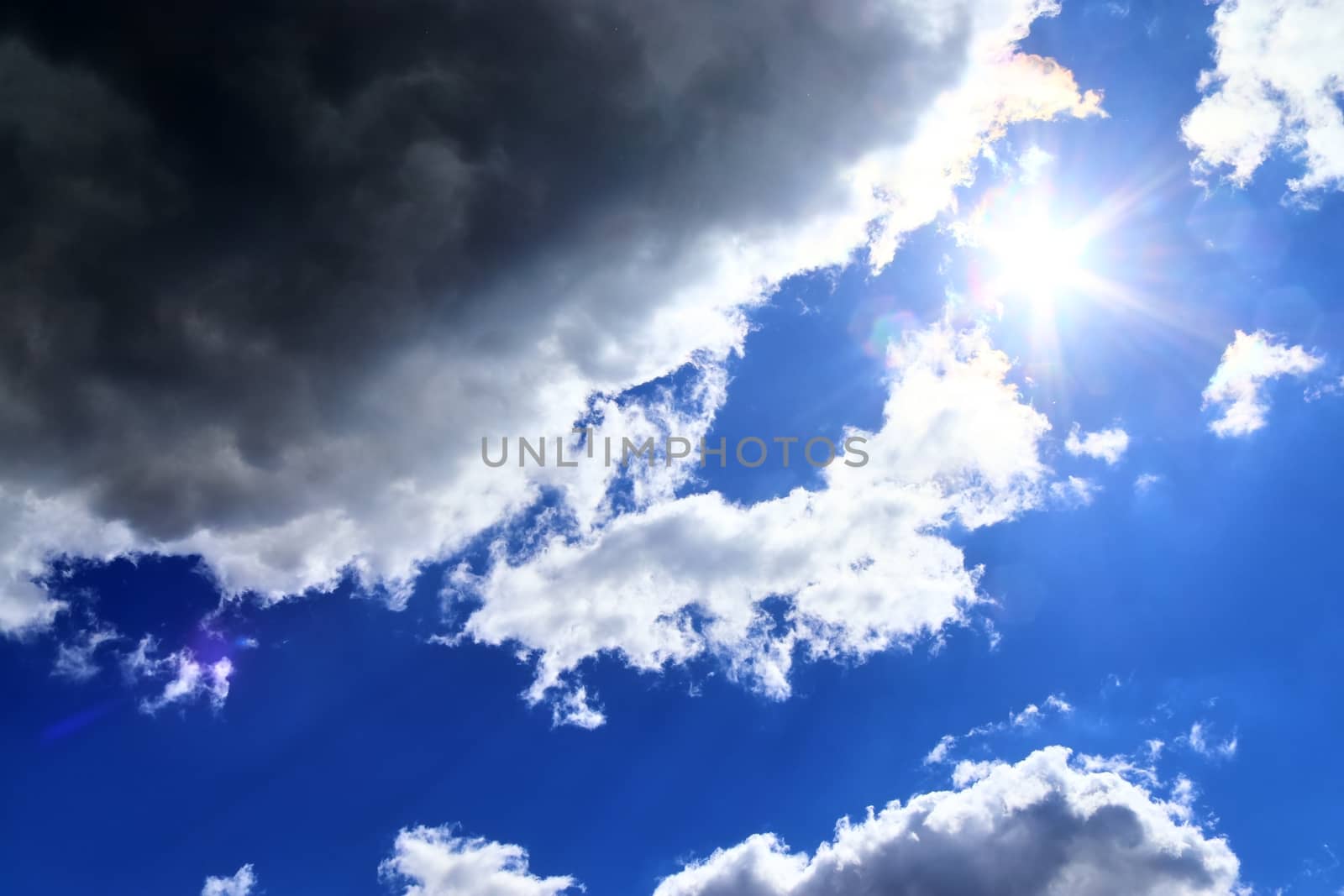 Beautiful view at bright sunbeams with some lens flares and clouds in a blue sky