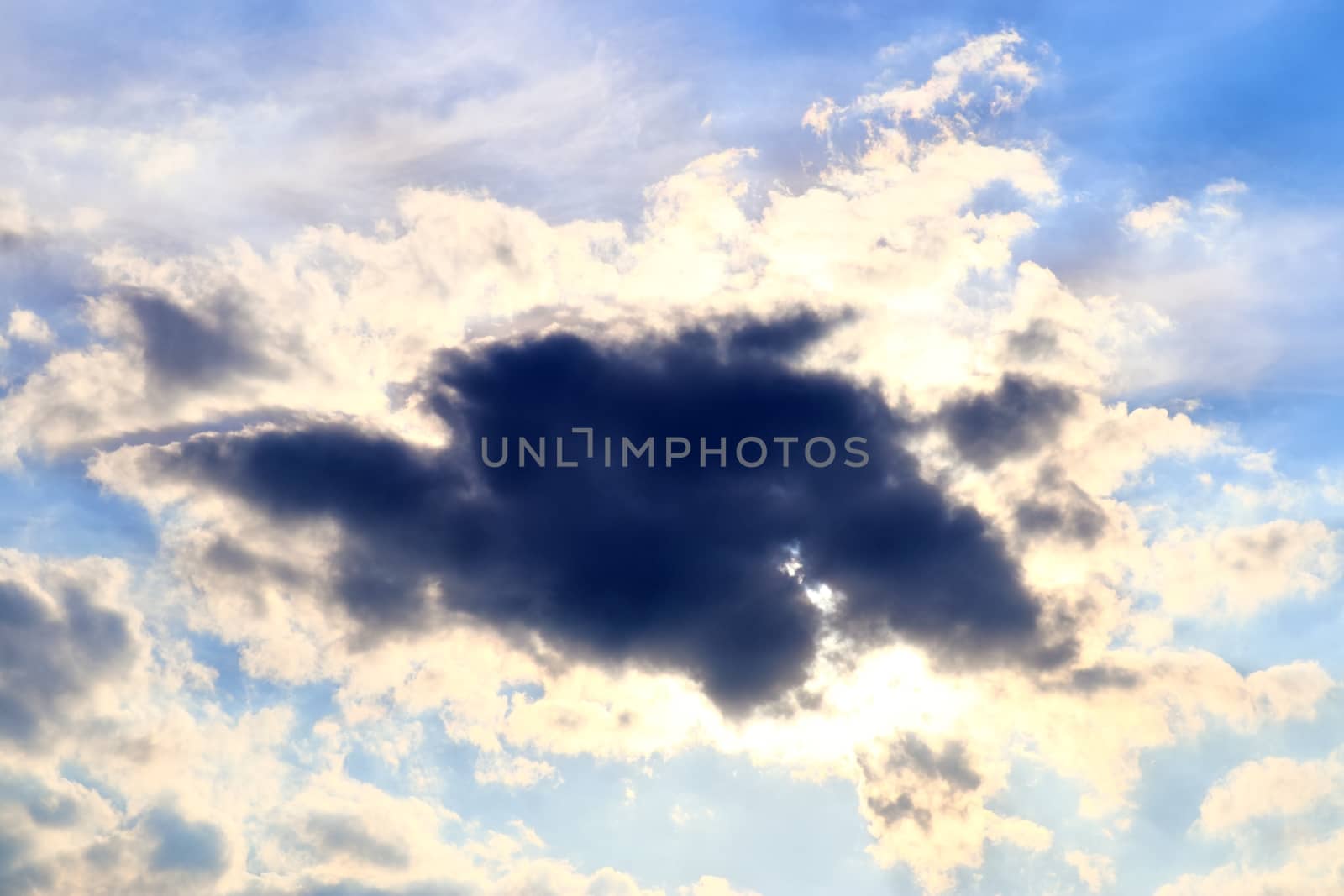 Beautiful view at bright sunbeams with some lens flares and clouds in a blue sky