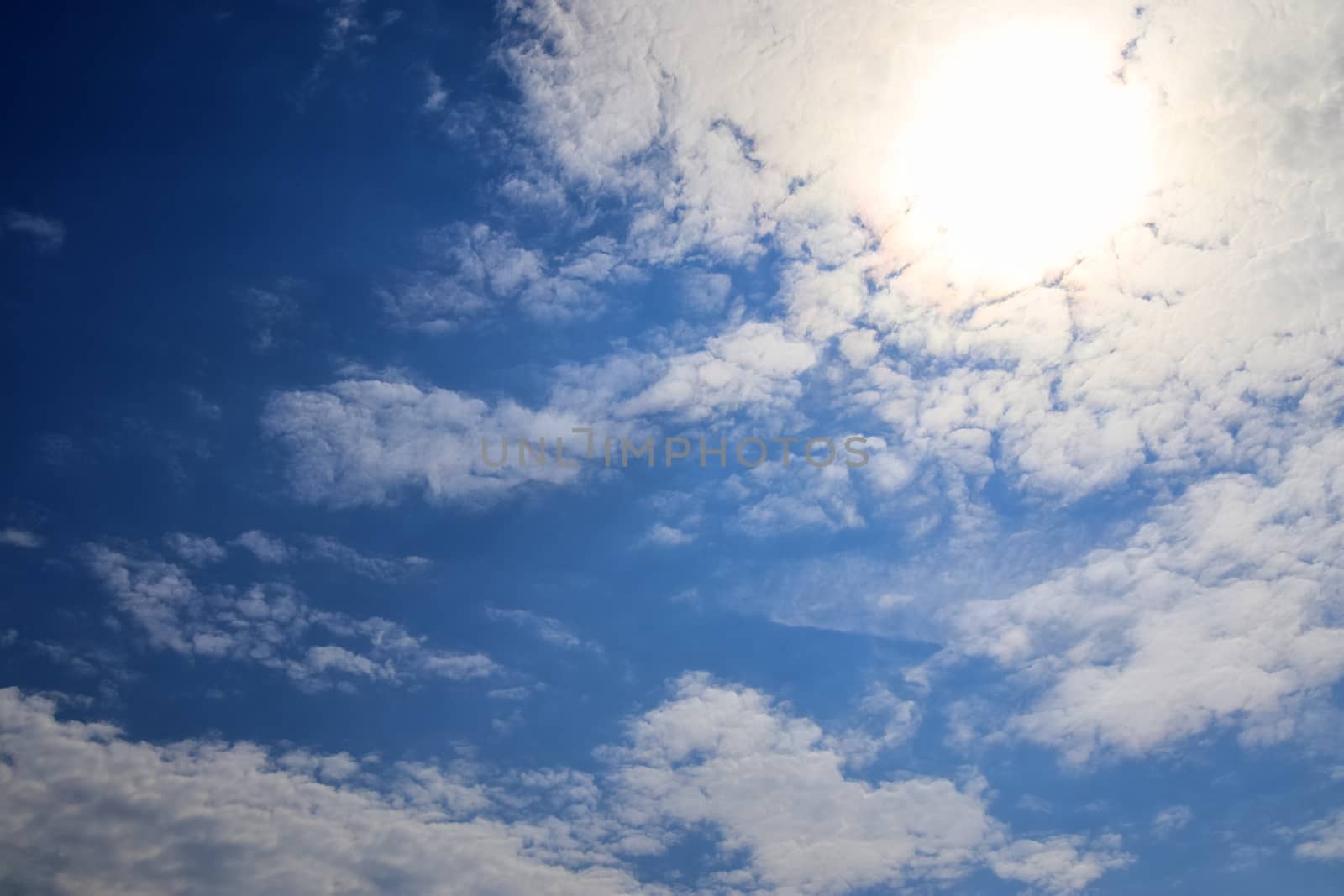 Beautiful view at bright sunbeams with some lens flares and clouds in a blue sky