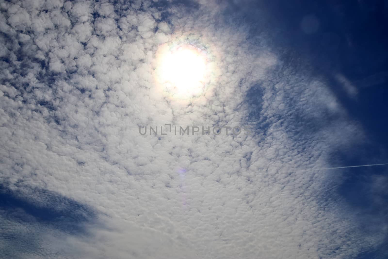 Beautiful view at bright sunbeams with some lens flares and clouds in a blue sky