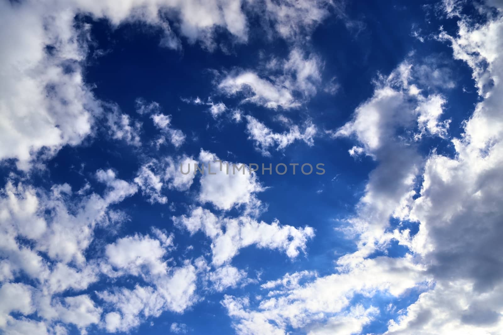 Beautiful view at bright sunbeams with some lens flares and clouds in a blue sky