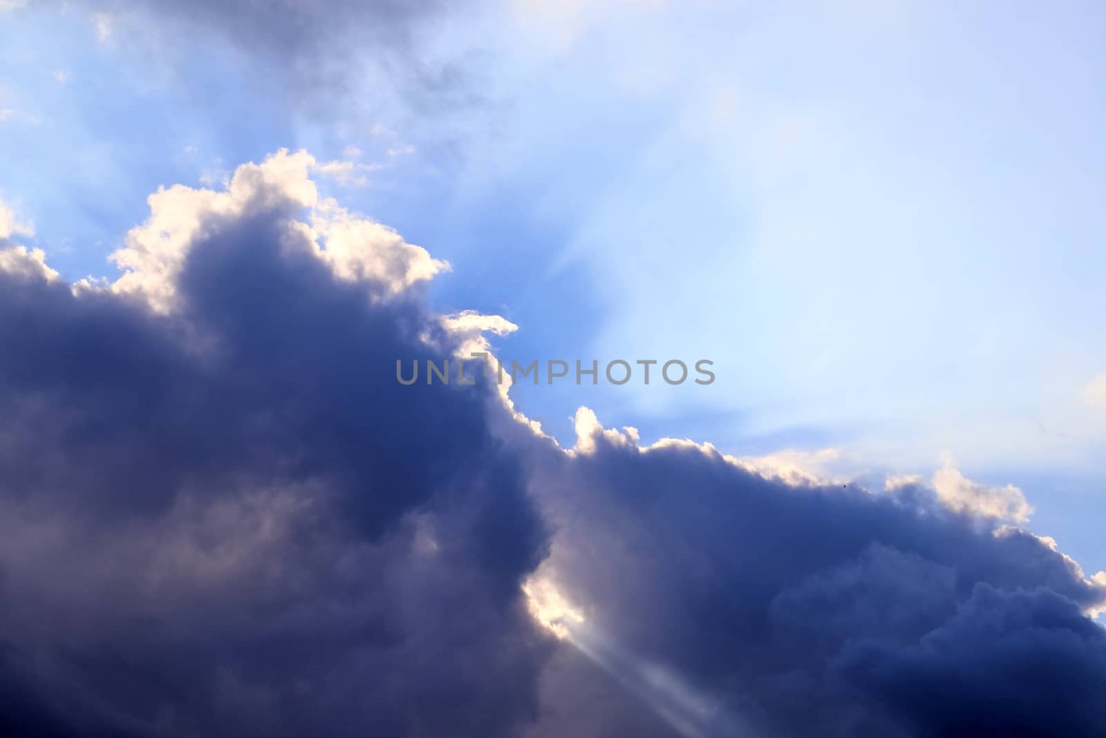 Beautiful view at bright sunbeams with some lens flares and clouds in a blue sky