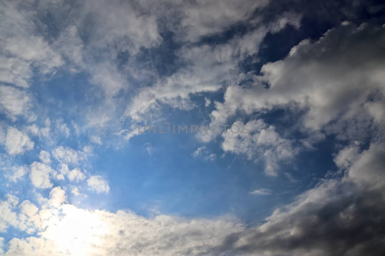 Beautiful view at bright sunbeams with some lens flares and clouds in a blue sky