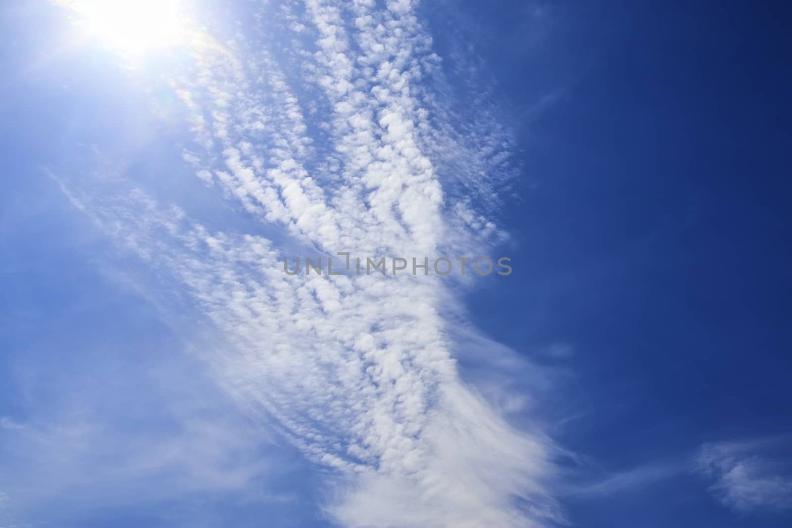 Beautiful view at bright sunbeams with some lens flares and clouds in a blue sky