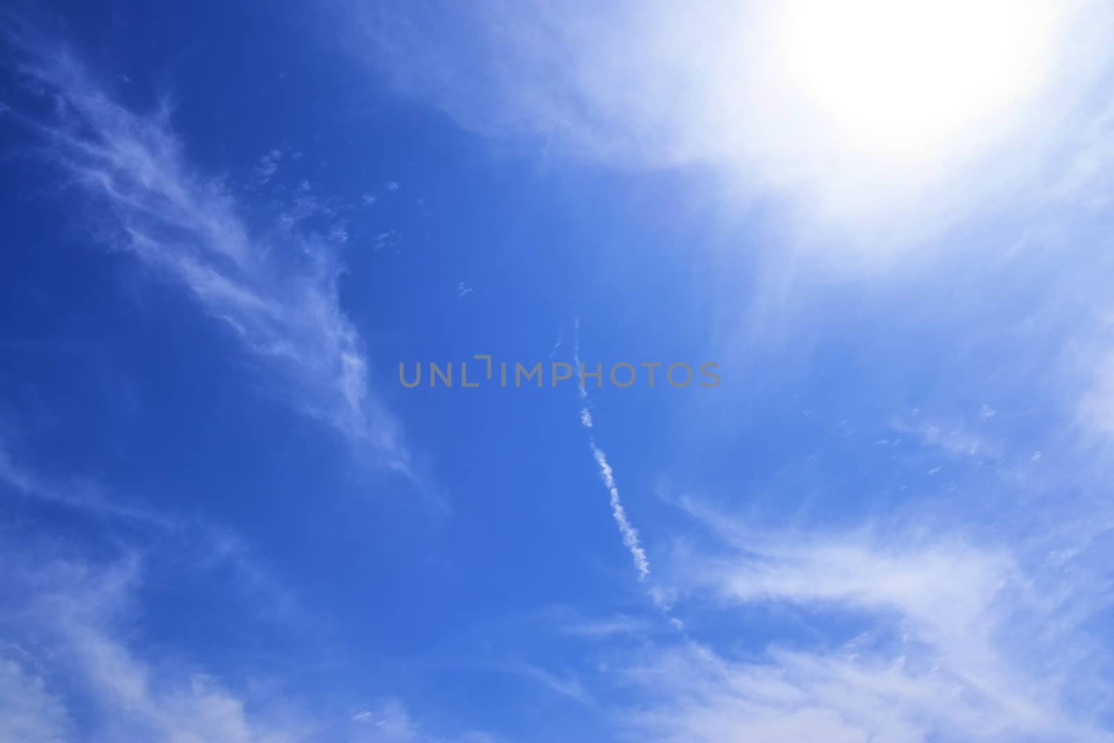 Beautiful view at bright sunbeams with some lens flares and clouds in a blue sky