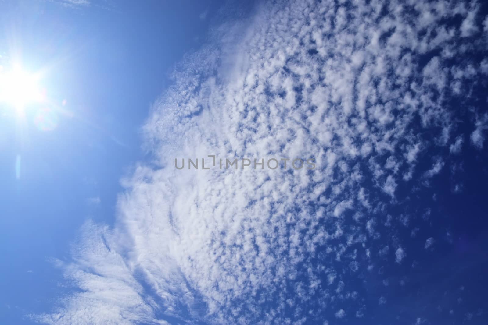 Beautiful view at bright sunbeams with some lens flares and clouds in a blue sky